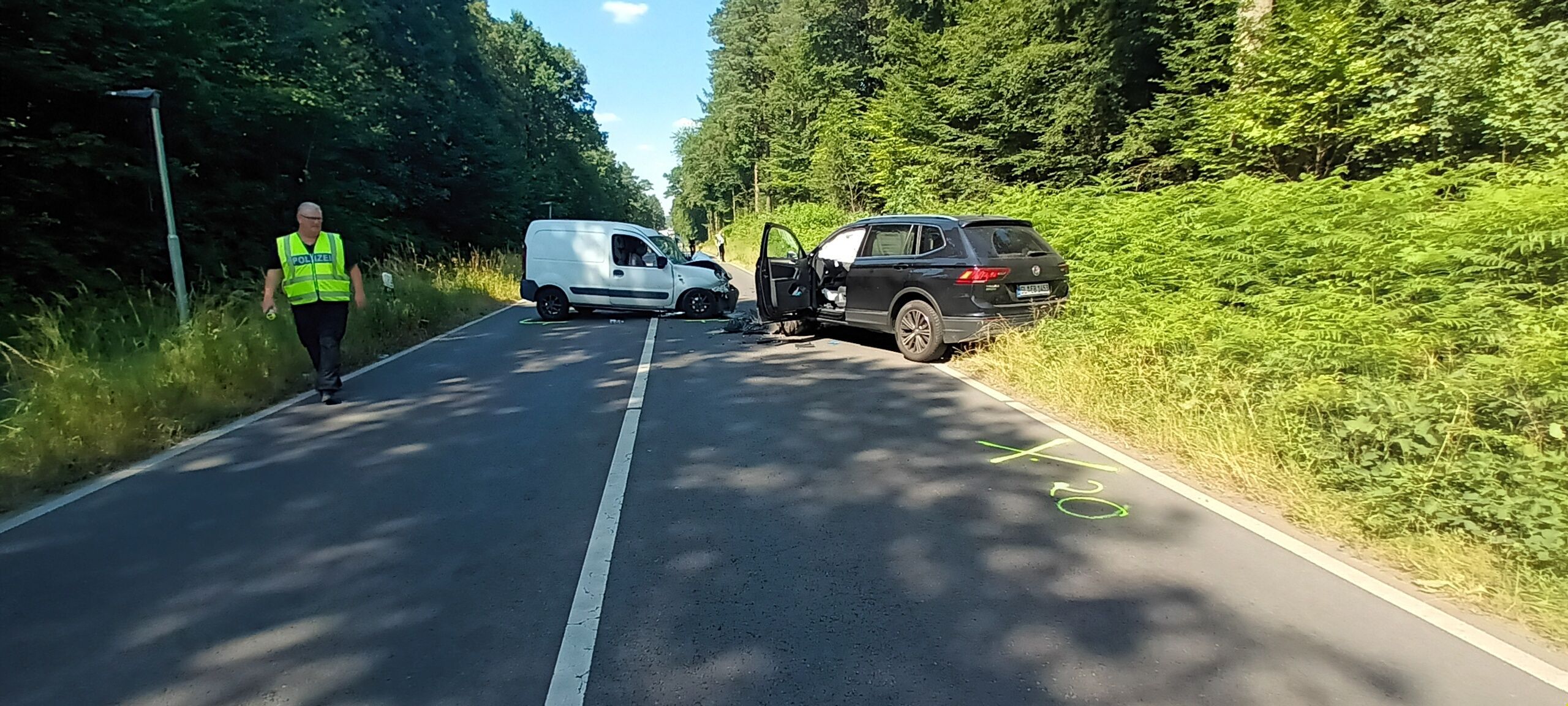 Zwei Unfallautos stehen auf dem Refrather Weg in Bergisch Gladbach. Ein Polizist sucht nach Spuren.