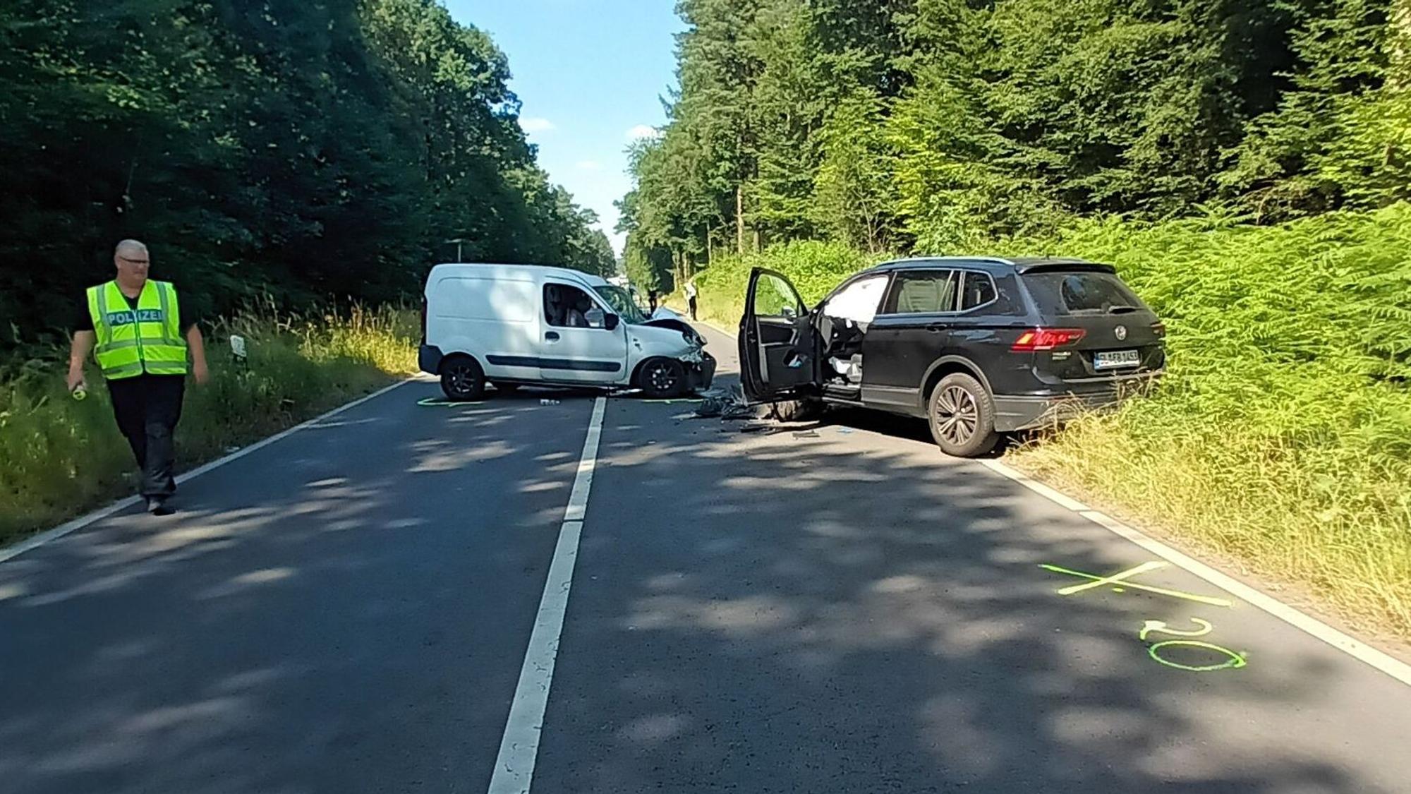 Zwei Unfallautos stehen auf dem Refrather Weg in Bergisch Gladbach. Ein Polizist sucht nach Spuren.