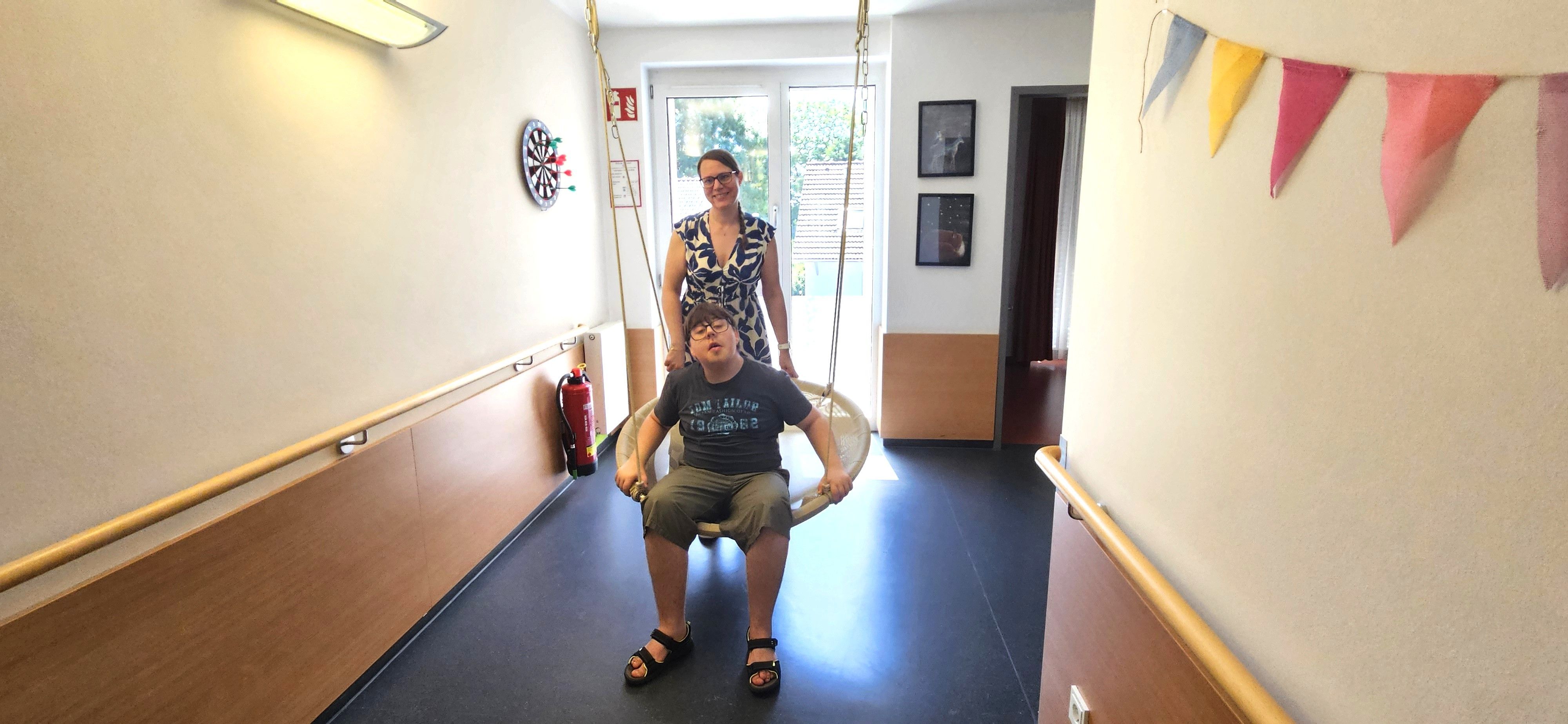 Das Foto zeigt Jonas in einem Schaukelnest, dahinter seine Mutter Nicole Fuchs.