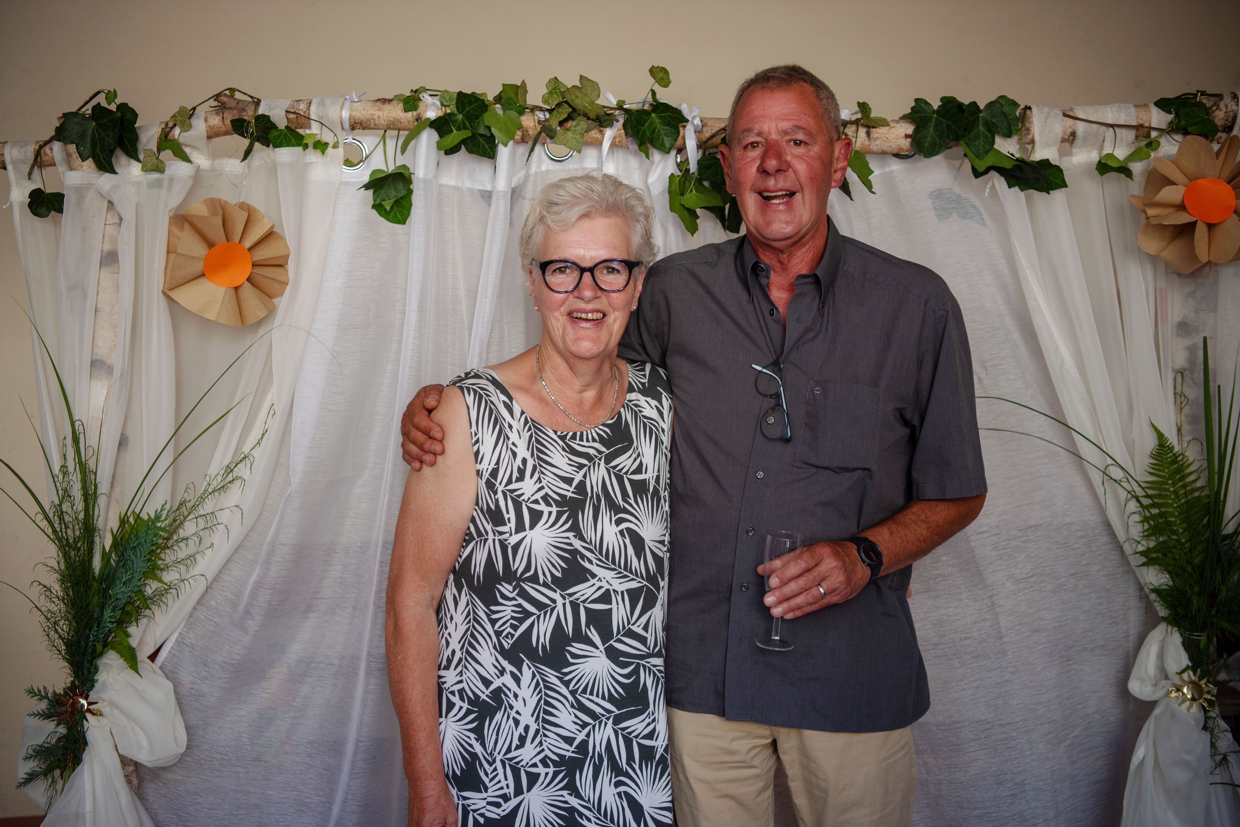 Birgit und Klaus Bleiniger haben sich nach 15 Jahren Ehe nund auch kirchlich das Ja-Wort gegeben und stehen Arm in Arm vor einem Dekorierten Bogen.