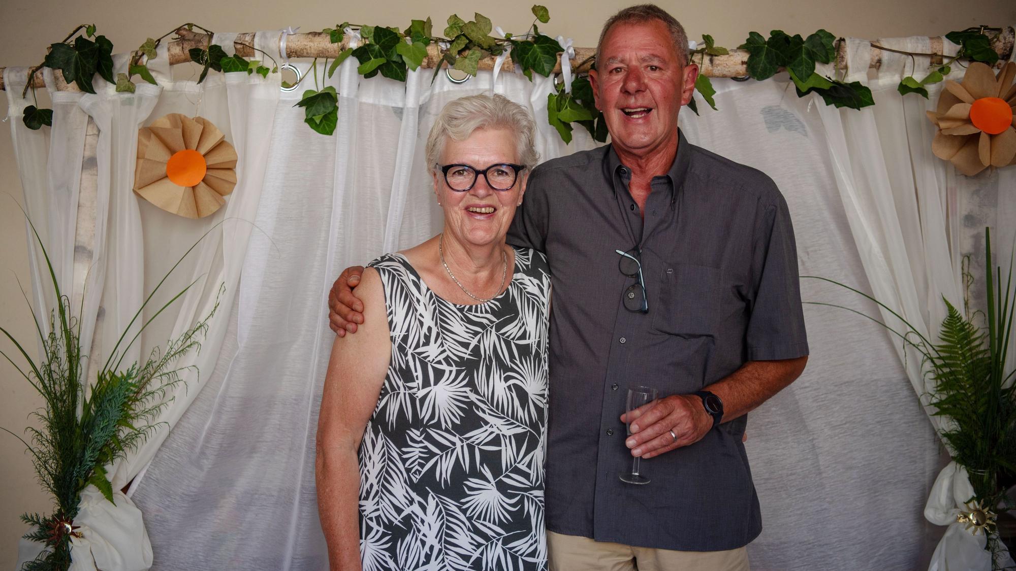 Birgit und Klaus Bleiniger haben sich nach 15 Jahren Ehe nund auch kirchlich das Ja-Wort gegeben und stehen Arm in Arm vor einem Dekorierten Bogen.