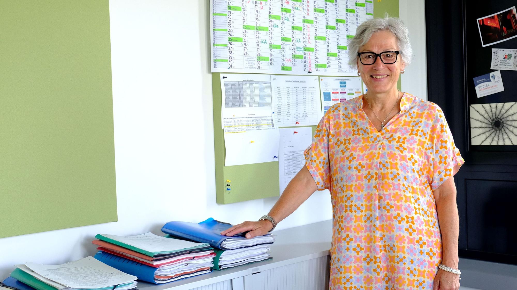 Iris Poth mit einem orange-gemusterten Sommerkleid in ihrem Büro in der Euskirchener Kreisverwaltung.
