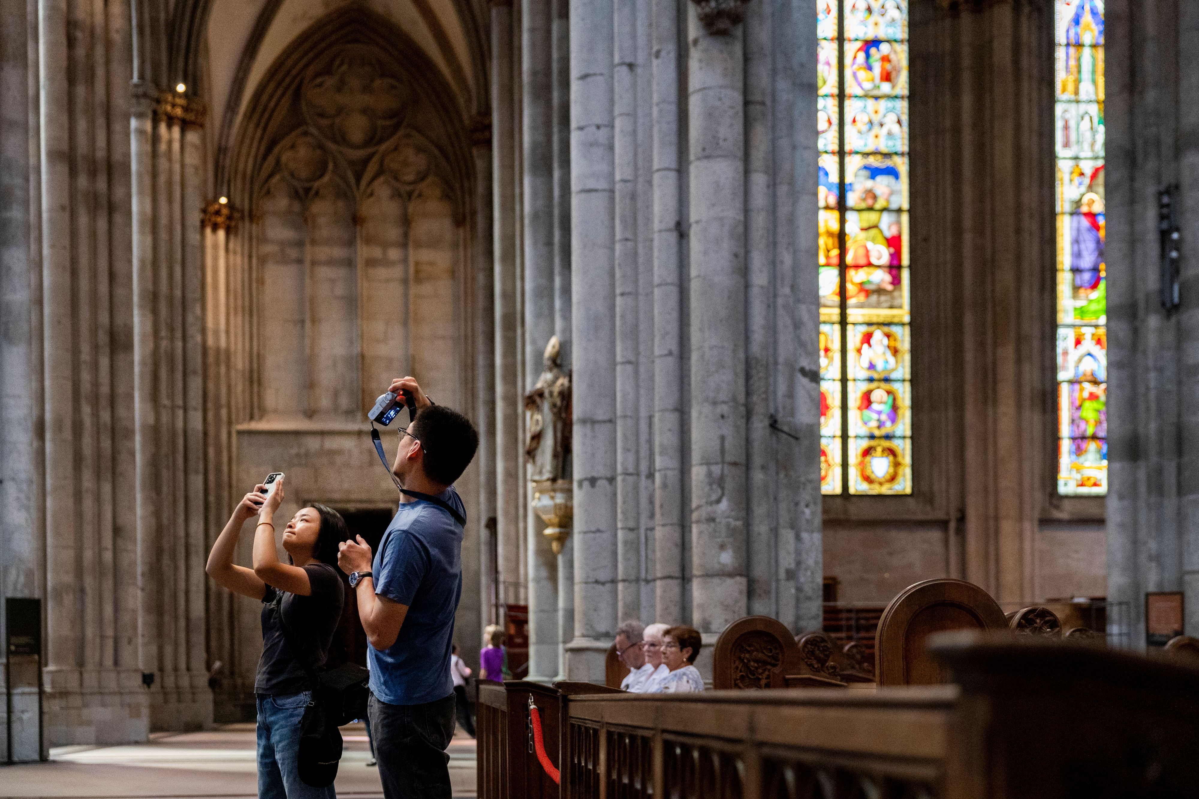 Touristen fotografieren während einer Besichtigung im Kölner Dom.