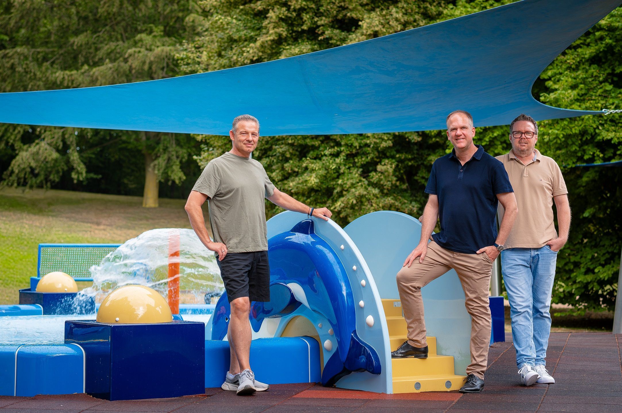 Das Foto zeigt die Vertreter der Stadt vor den farbenfrohen Spielgeräten auf dem neuen Wasserspielplatz.