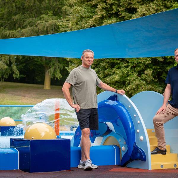 Das Foto zeigt die Vertreter der Stadt vor den farbenfrohen Spielgeräten auf dem neuen Wasserspielplatz.