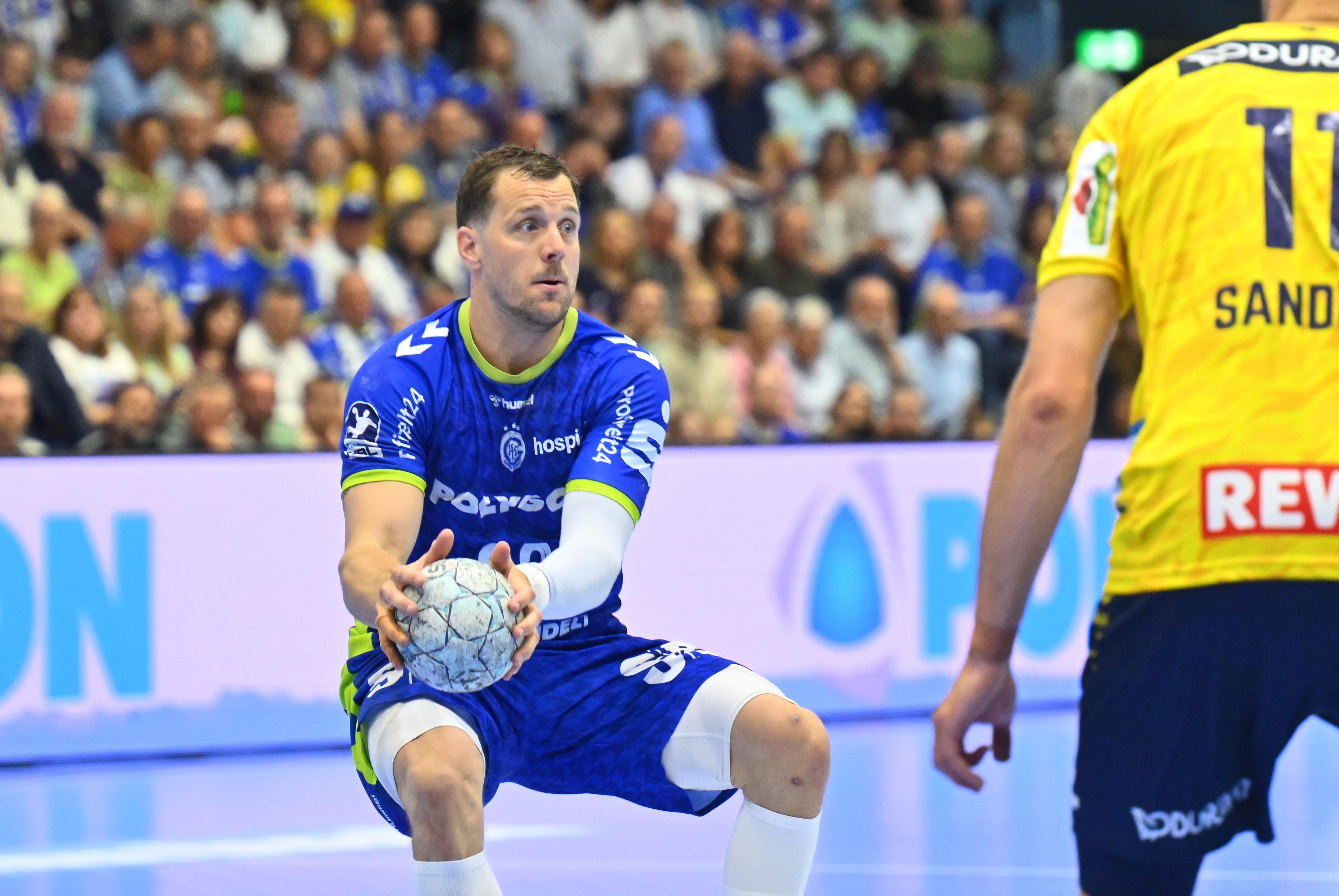 Der Rückraumspieler hält den Ball in beiden Händen.