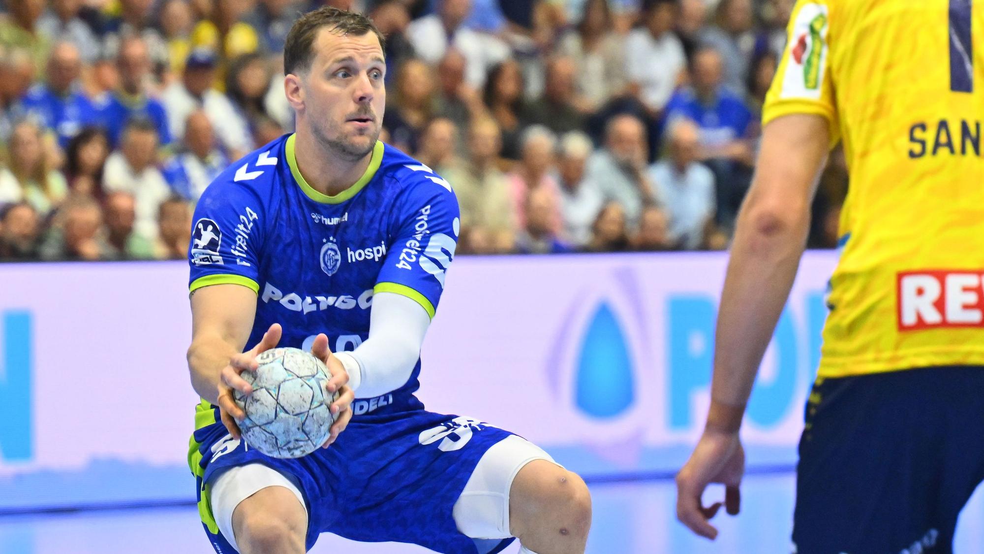 Der Rückraumspieler hält den Ball in beiden Händen.