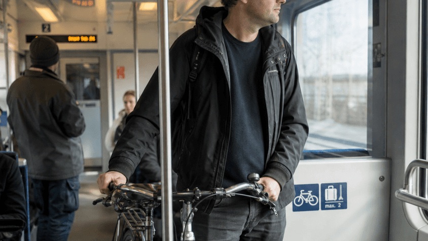 Ein Mann der mit seinem Fahrrad in der Bahn fährt.