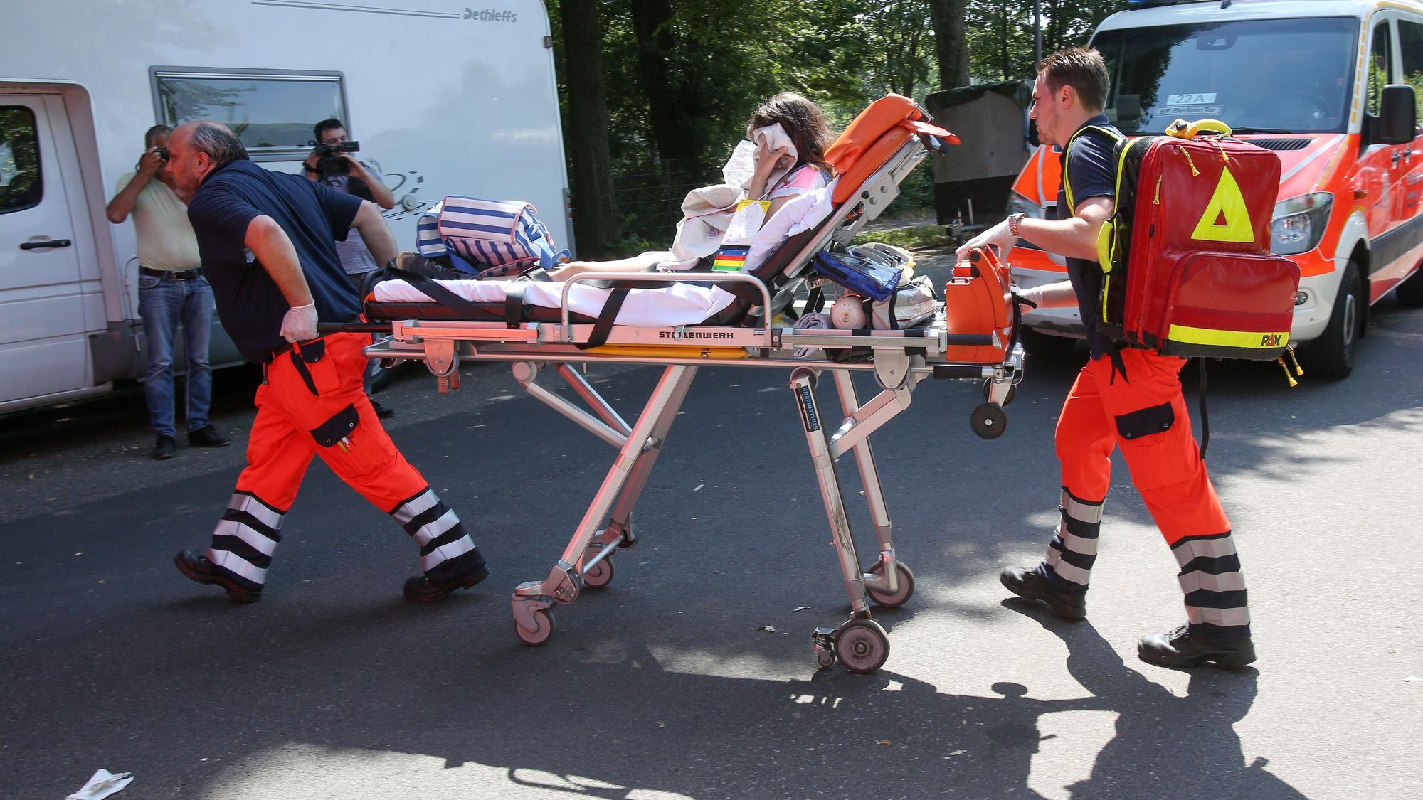 Rettungssanitäter bringen eine Schülerin zu einem Rettungswagen.