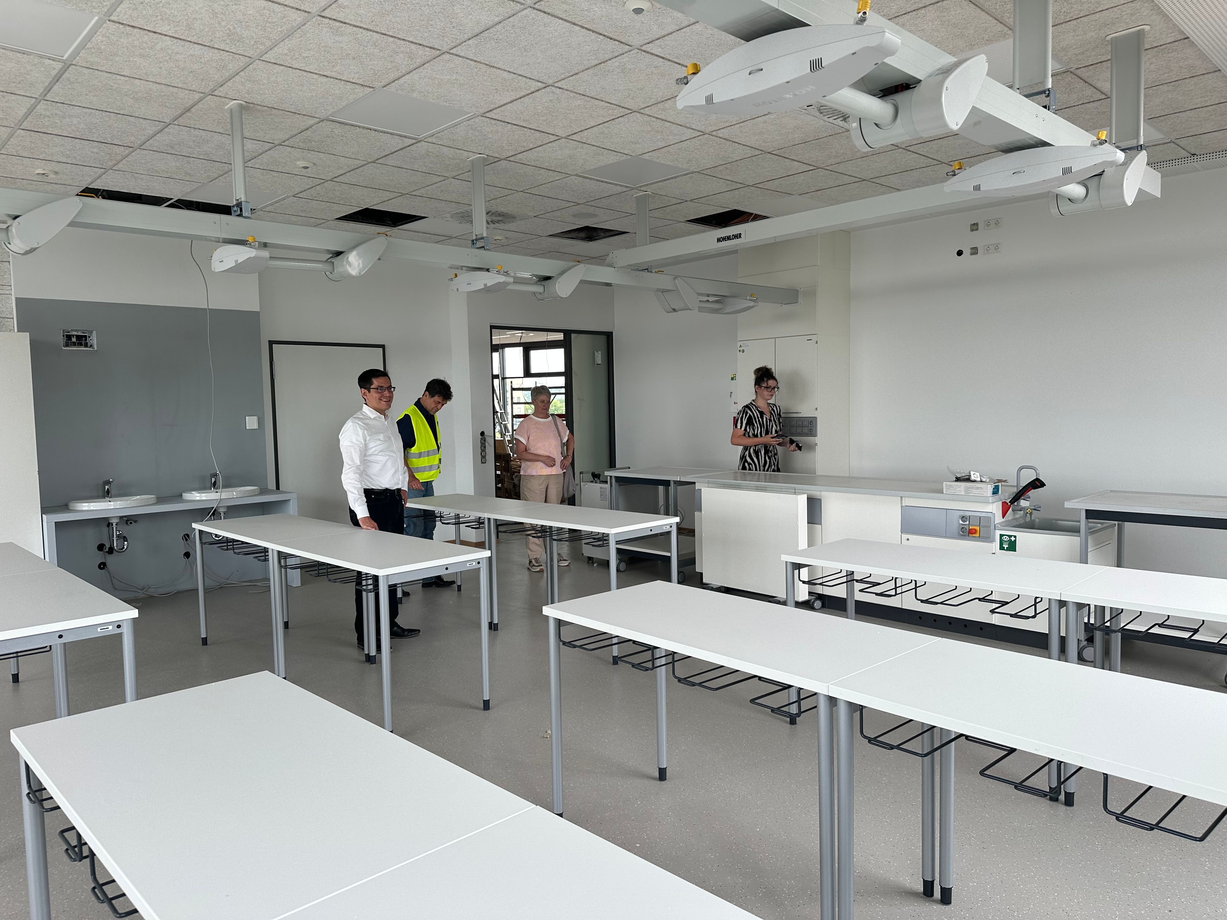 Blick in einen Klassenraum für Naturwissenschaften. Die Gasversorgung für Bunsenbrenner kommt von den Versorgungsmodulen an der Decke.