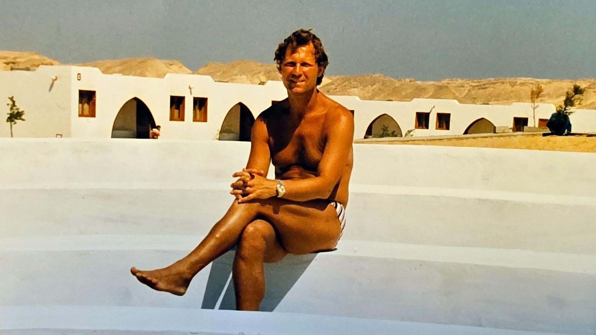 Ein junger Mann sitzt an einem Pool ohne Wasser.