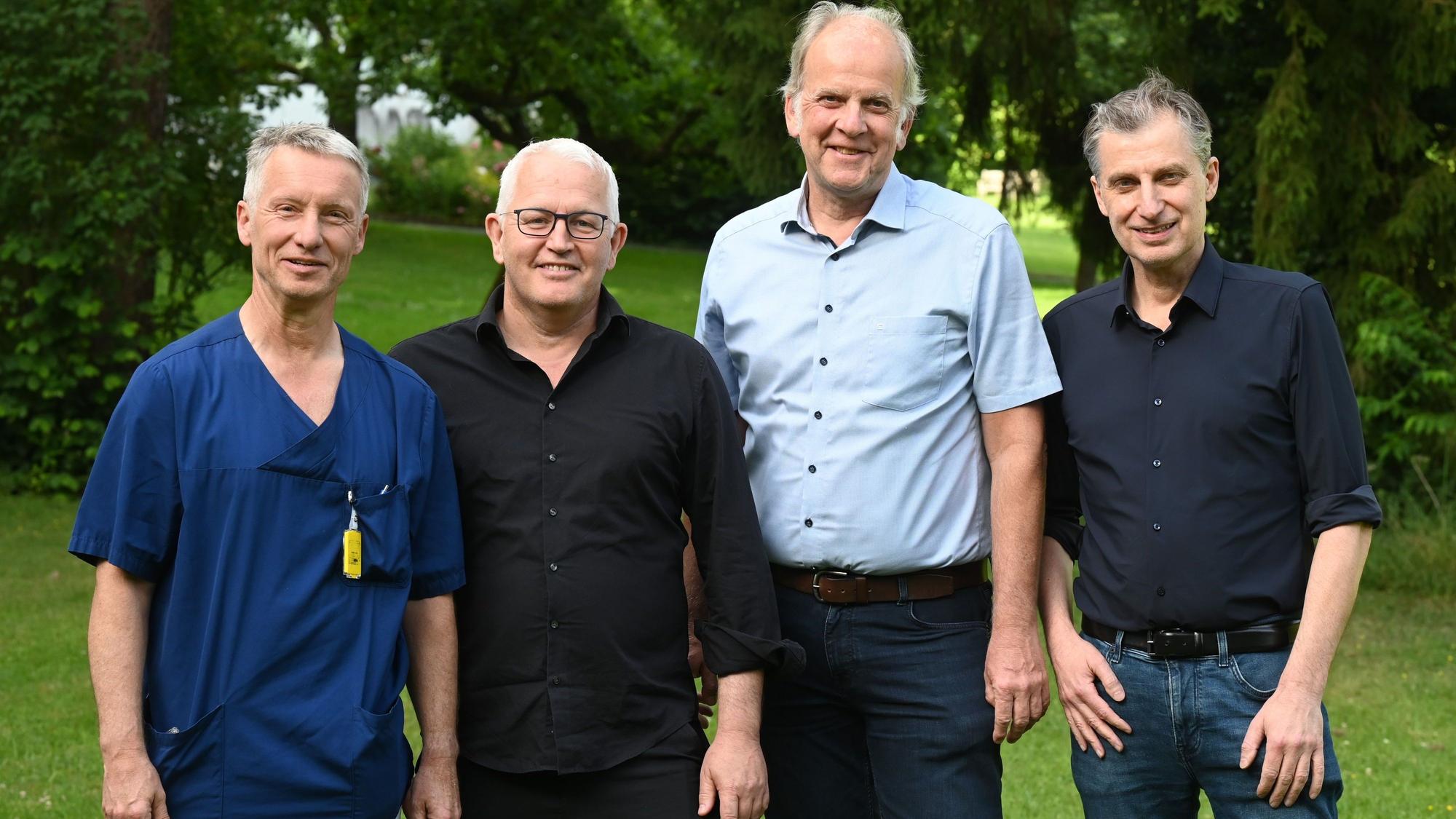 Vier Männer in einem Park schauen lächelnd in die Kamera