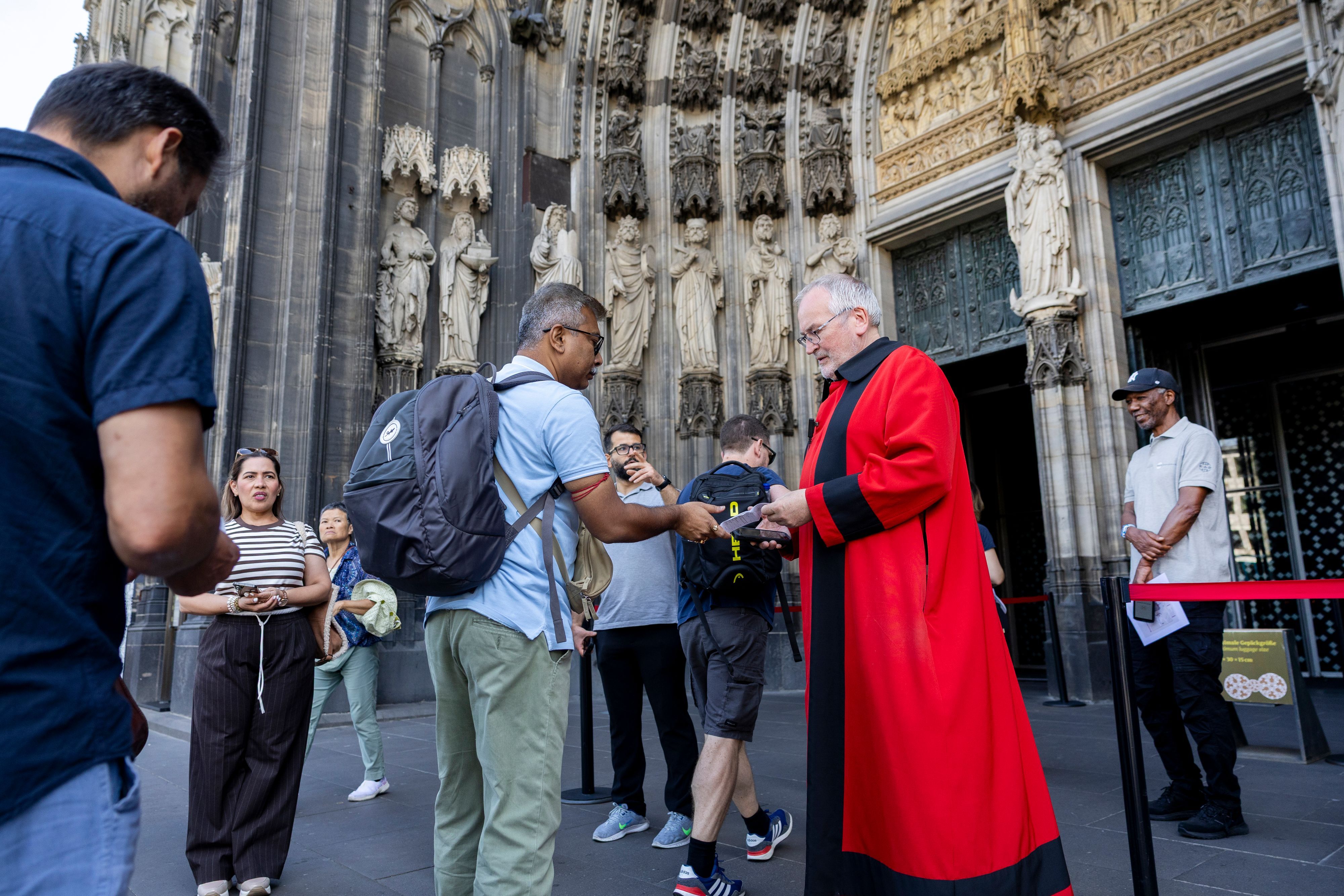 Ein Domschweizer kontrolliert am Westportal des Kölner Doms Eintrittskarten für die Kathedrale.