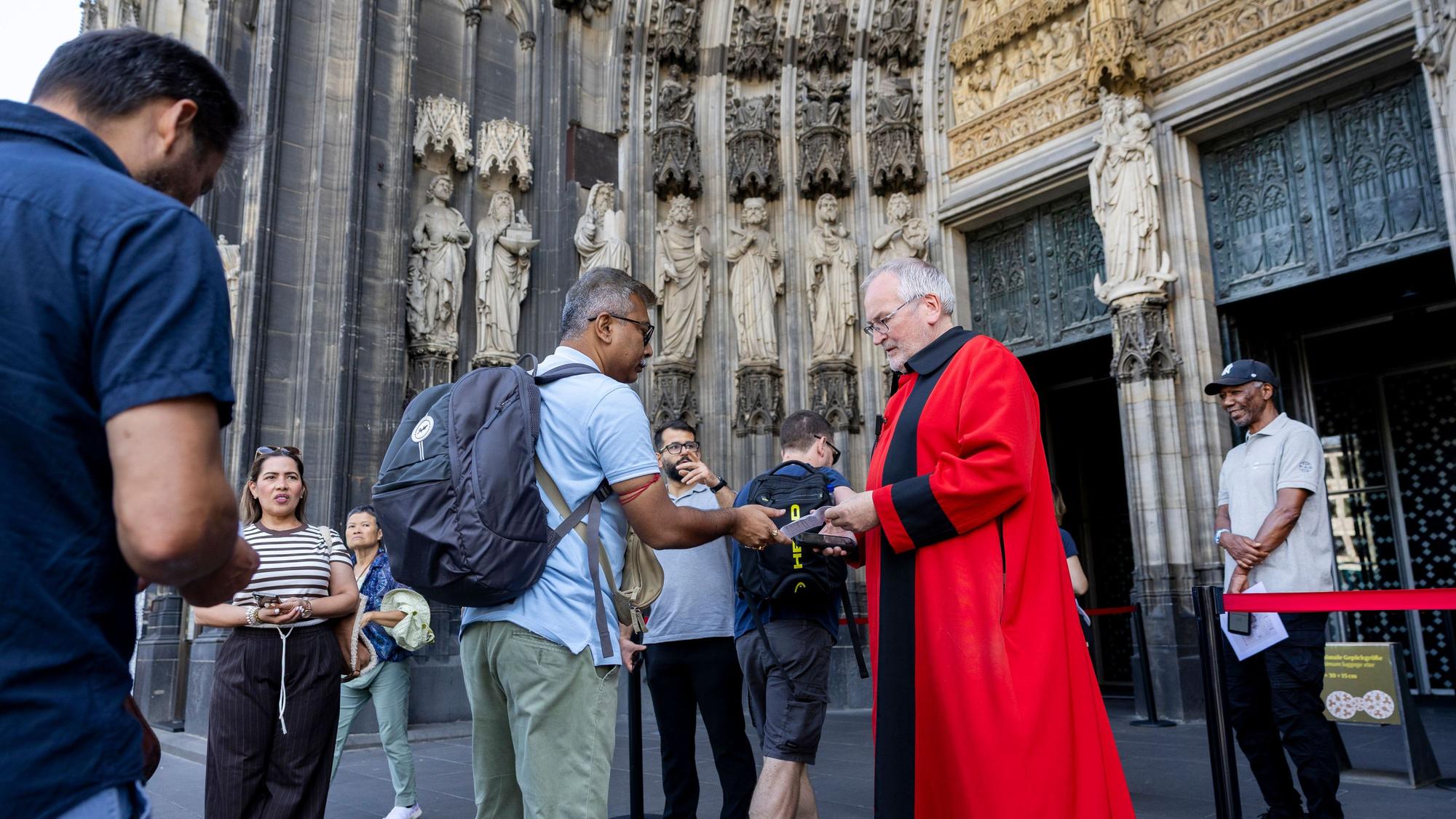 Ein Domschweizer kontrolliert am Westportal des Kölner Doms Eintrittskarten für die Kathedrale.