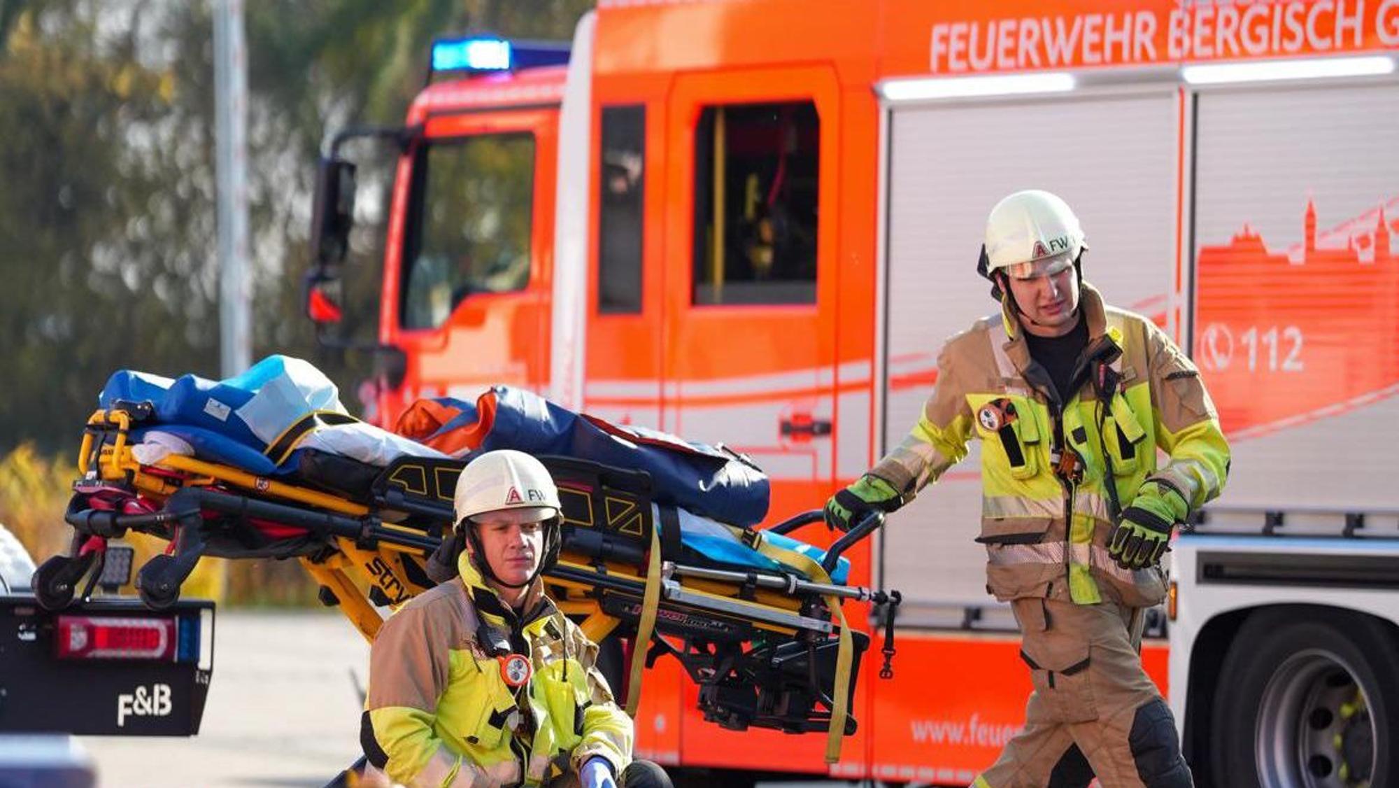 Ein Feuerwehrmann fährt eine Rettungstrage vor einem Löschfahrzeug vorbei.