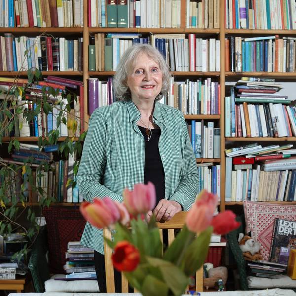 Renate Beisenherz-Galas steht vor einer übervollen Bücherwand und lächelt in die Kamera.