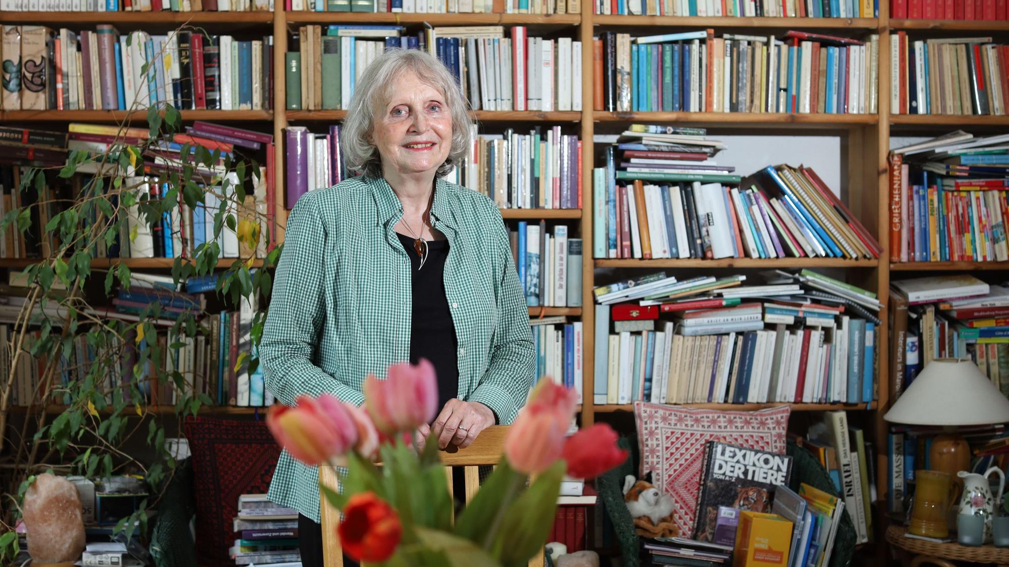 Renate Beisenherz-Galas steht vor einer übervollen Bücherwand und lächelt in die Kamera.