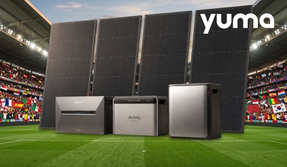 Drei Heimspeicher der Marken Anker Solix, EcoFlow und Jackery sowie vier aufgestellte Solarmodule vor der Kulisse eines Fußballstadions mit vielen Länder-Flaggen im Hintergrund.