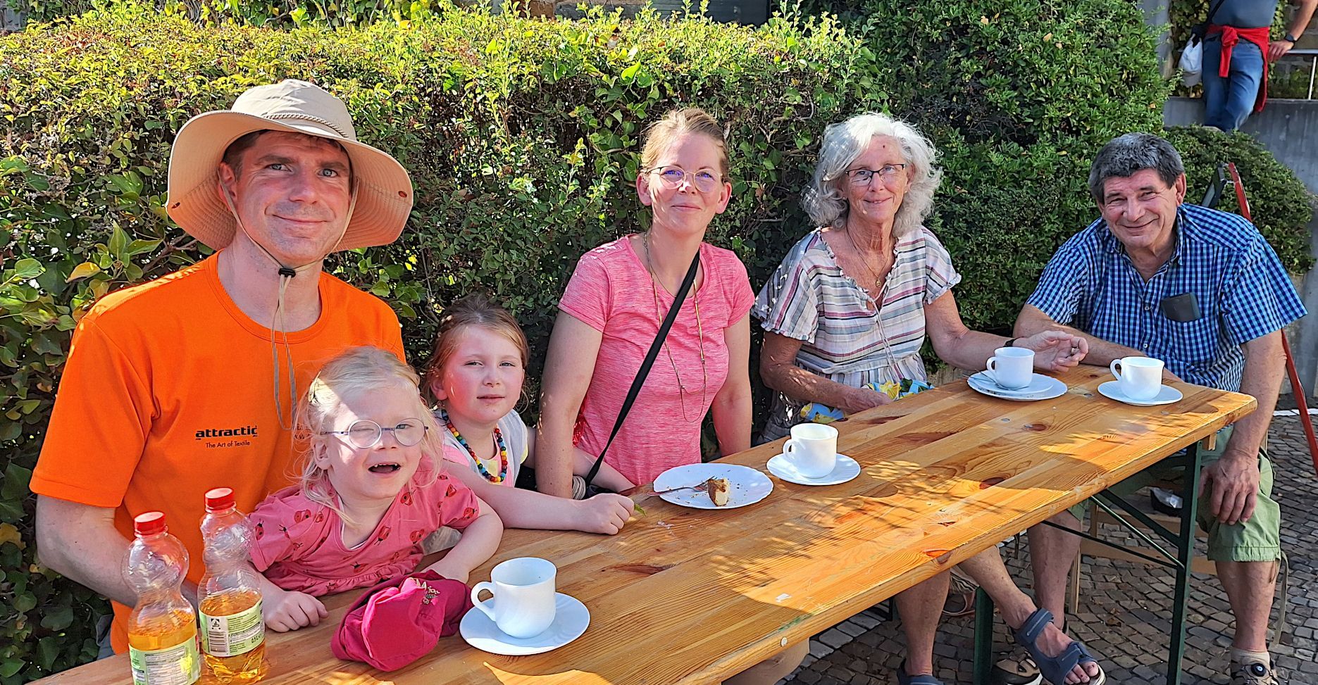 Die Familie sitzt an einem Bierzelttisch und trinke Kaffee und Apfelschorle.