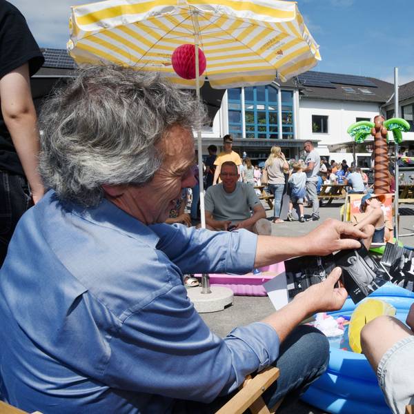 Lehrer und Schüler nehmen in Liegestühlen auf dem Schulhof Platz und erinnern sich mit historischen Fotos und Erzählungen an vergangene Schulzeiten.