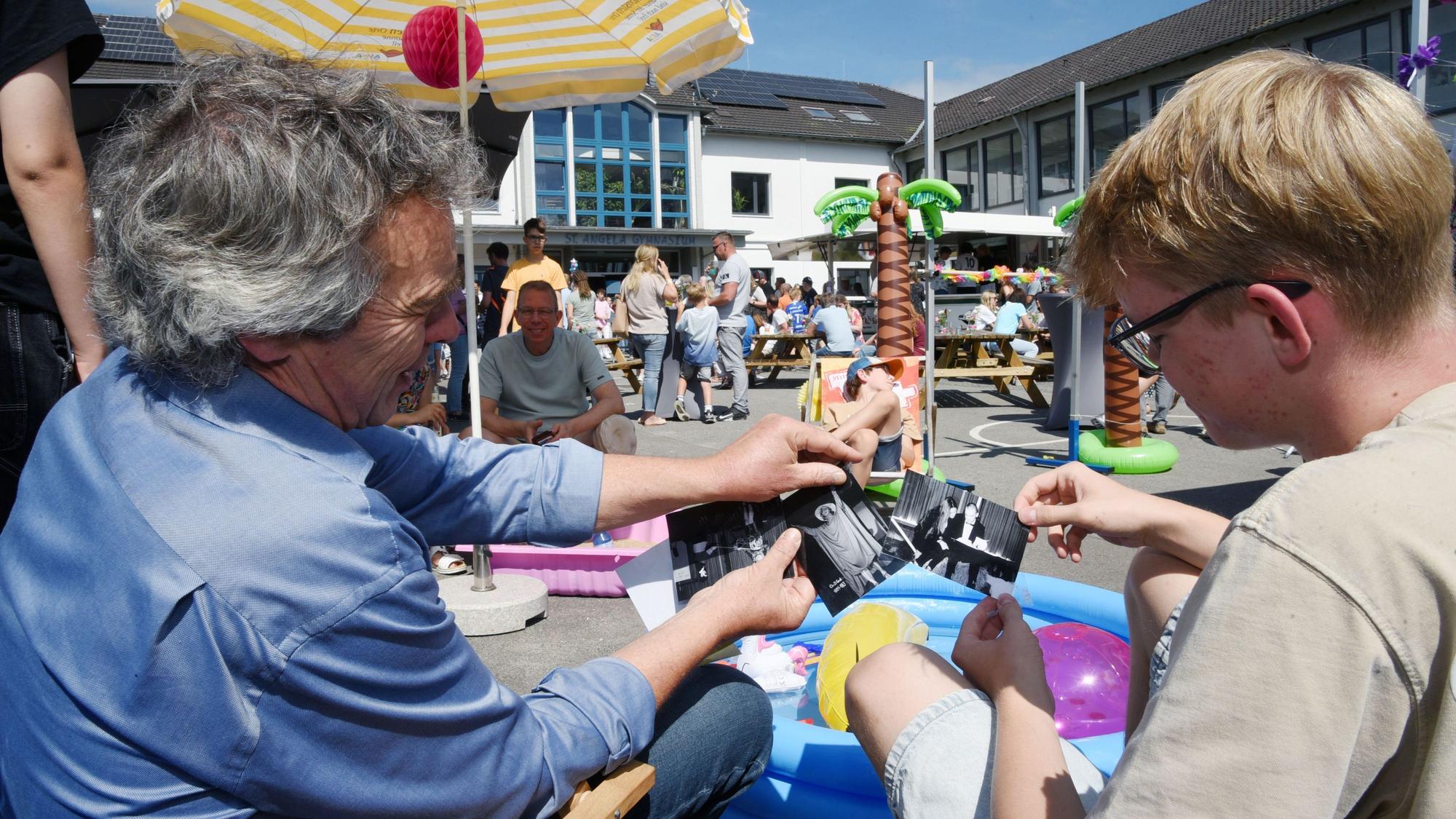 Lehrer und Schüler nehmen in Liegestühlen auf dem Schulhof Platz und erinnern sich mit historischen Fotos und Erzählungen an vergangene Schulzeiten.