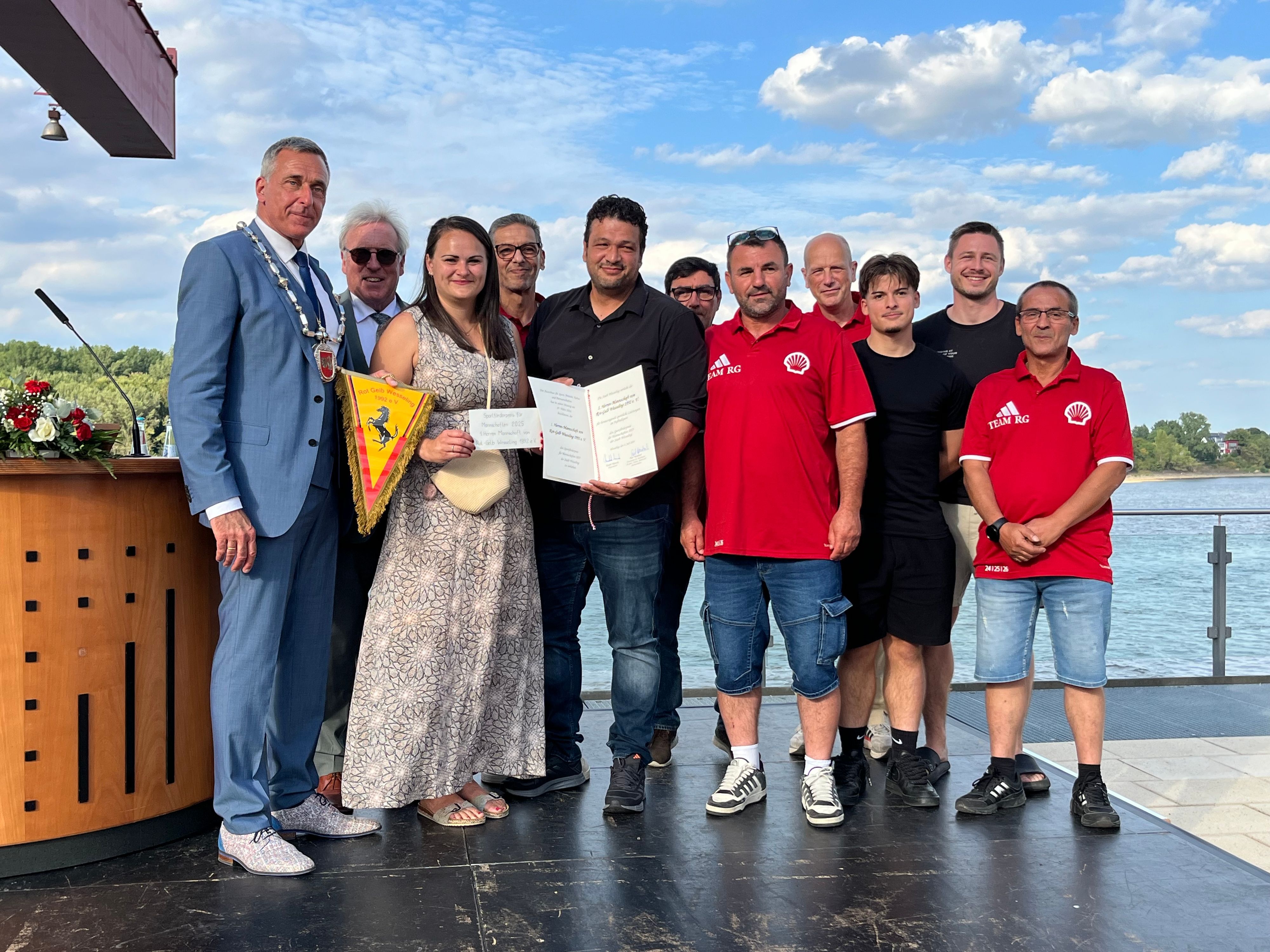 Eine Frau und zehn Männer posieren fürs Foto.