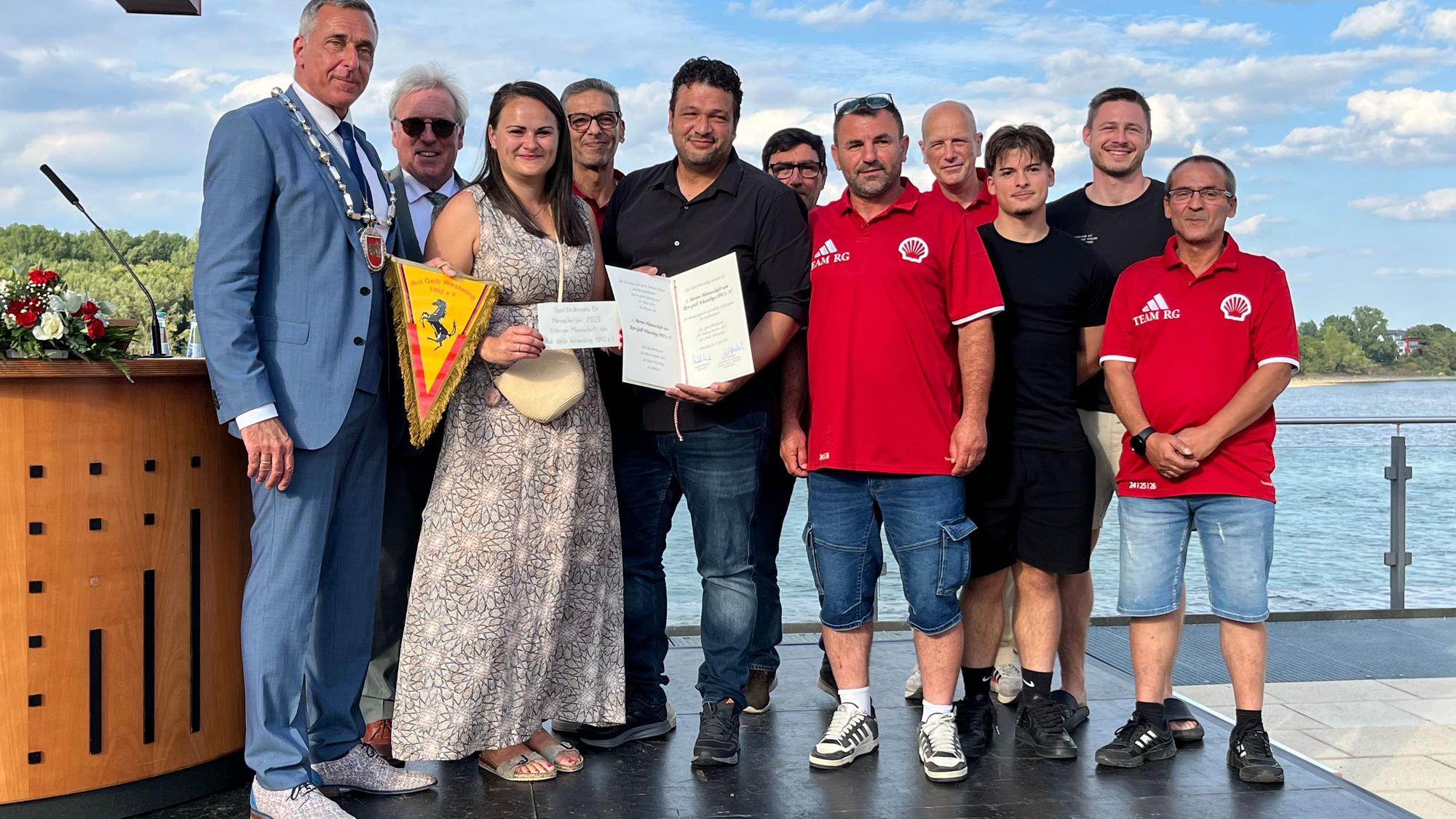 Eine Frau und zehn Männer posieren fürs Foto.