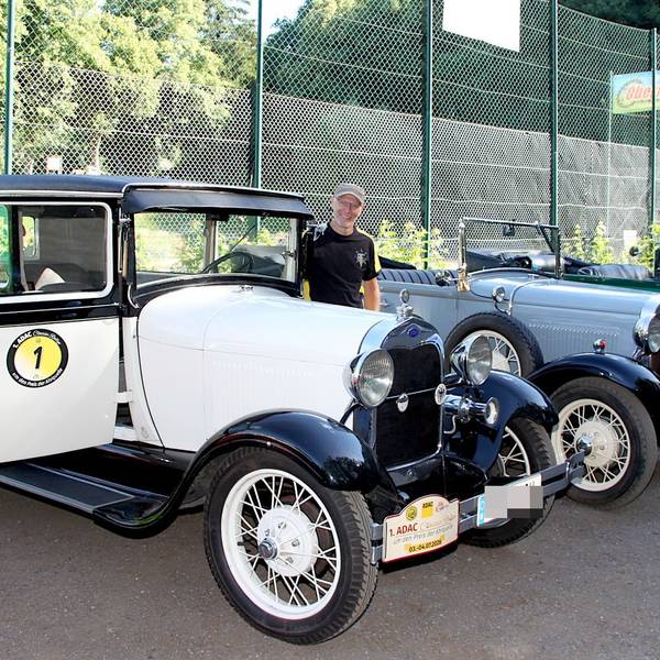 Zwei Männer stehen neben einer Reihe von Oldtimern.