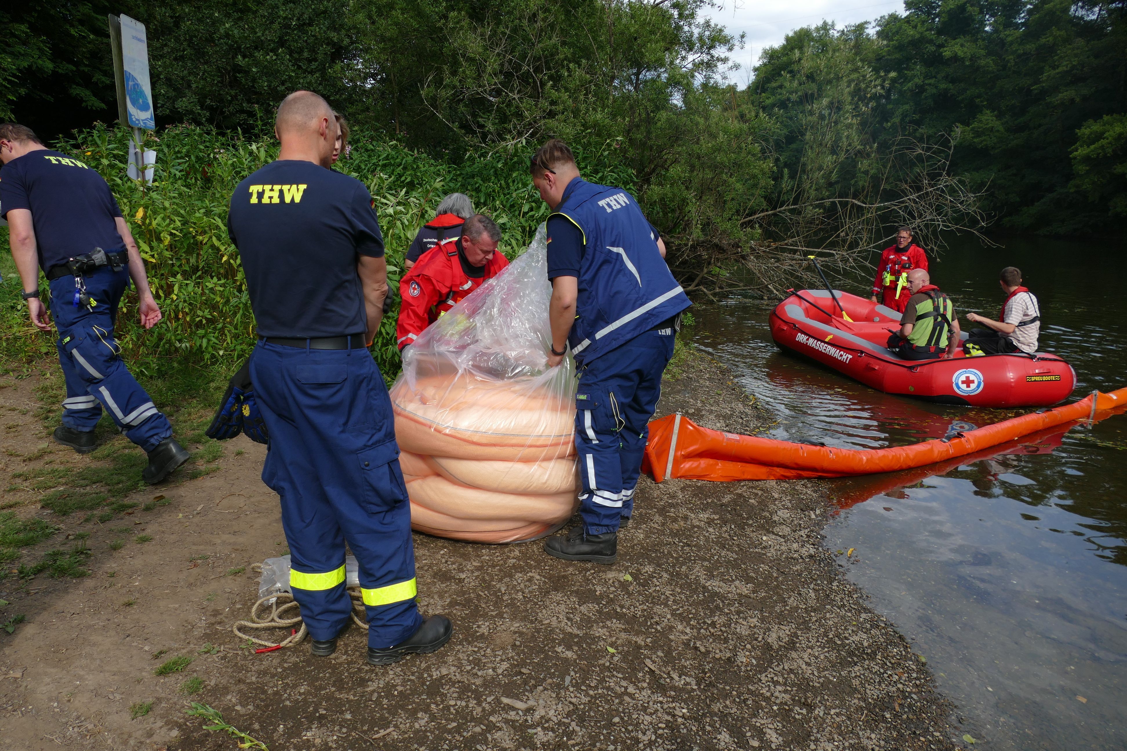 Mit einem Boot bringen die Einsatzkräfte Saugkörper auf der Sieg aus.