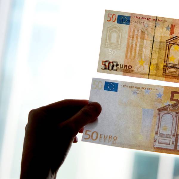 Ein echter und ein falscher Fünfzig-Euro-Schein werden gegen das Licht gehalten.