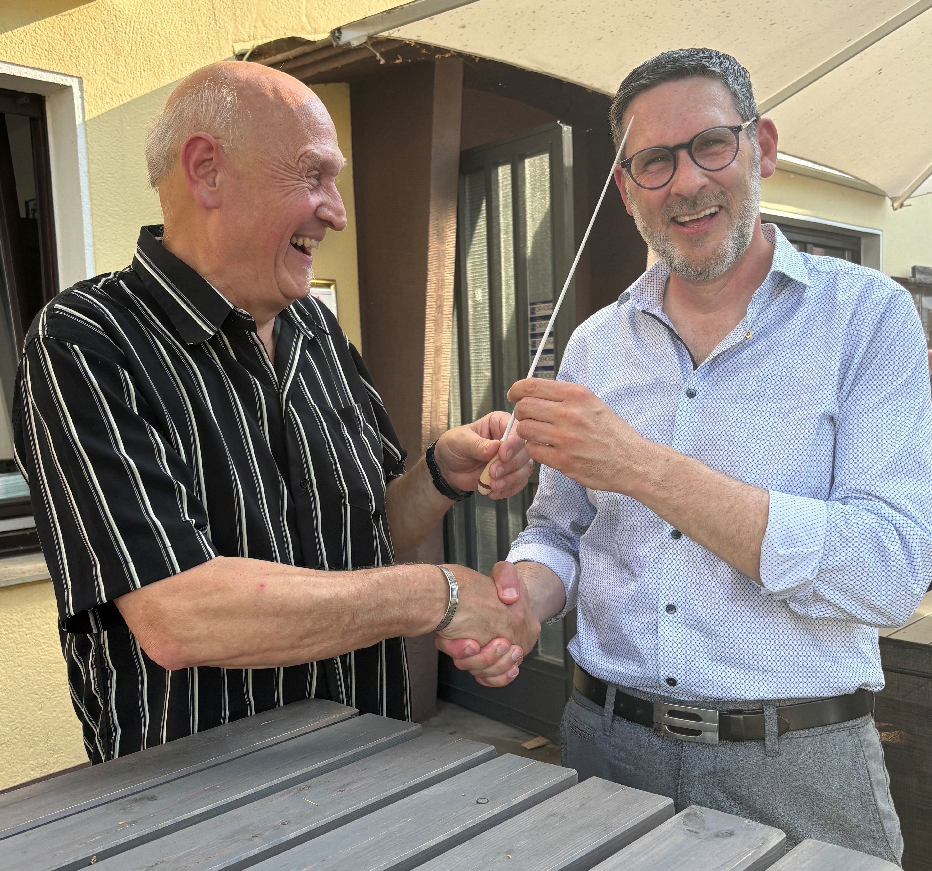 Das Foto zeigt den alten und den neuen Präsidenten des Lions-Clubs mit einem Taktstock.