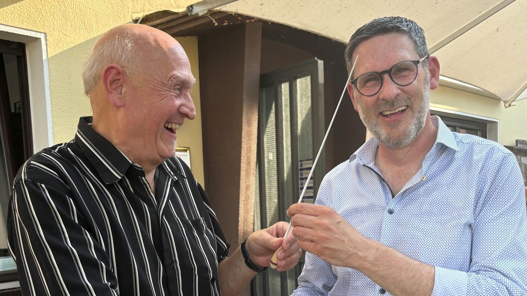 Das Foto zeigt den alten und den neuen Präsidenten des Lions-Clubs mit einem Taktstock.