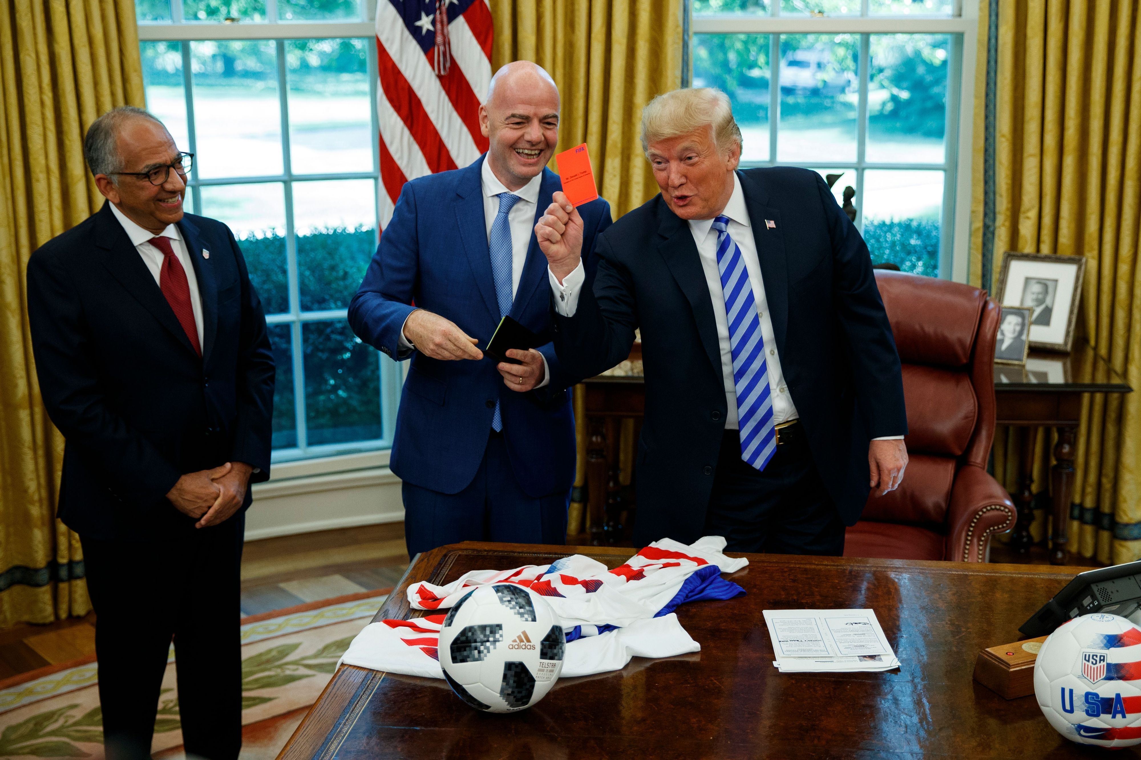 Präsident Donald Trump (r) hält während eines Treffens mit Fifa-Präsident Gianni Infantino (M) und US-Fußballverbandspräsident Carlos Cordeiro im Oval Office des Weißen Hauses eine rote Karte.