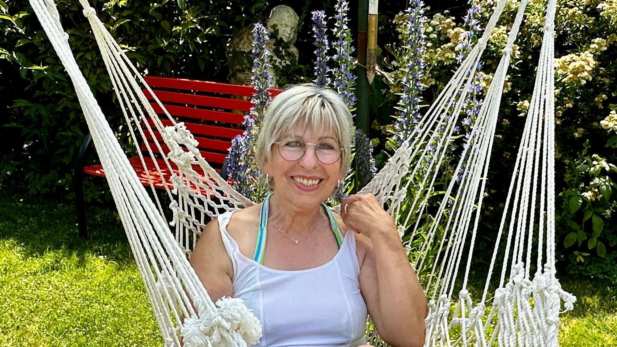 Eine Frau sitzt in einer Hängeschaukel in ihrem Garten.