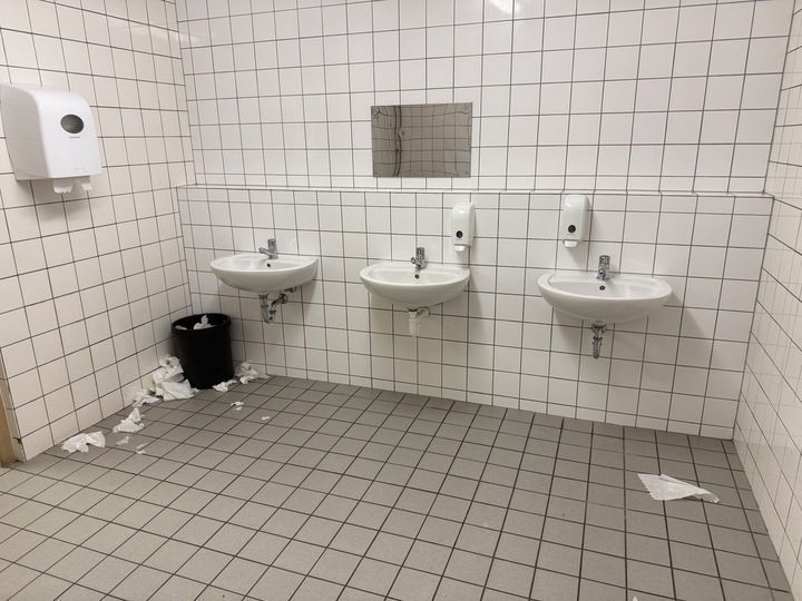 Das Bild zeigt eine Schultoilette. Trockentücher liegen auf dem Boden.