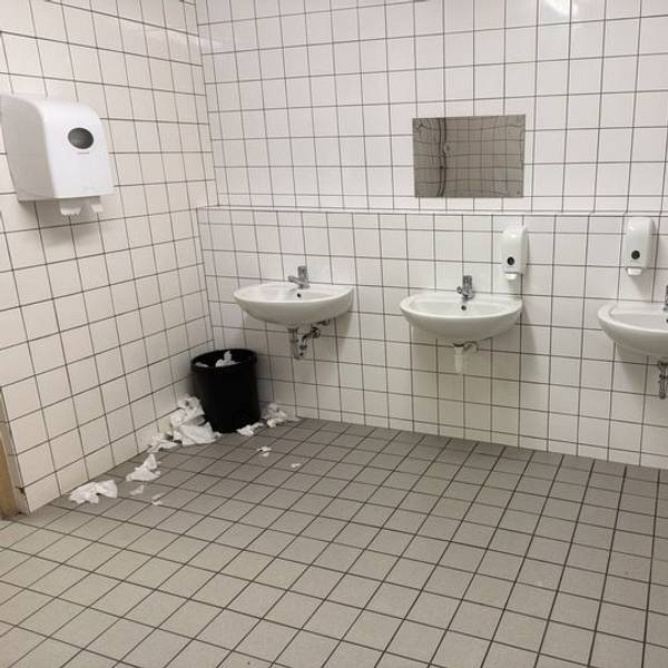 Das Bild zeigt eine Schultoilette. Trockentücher liegen auf dem Boden.