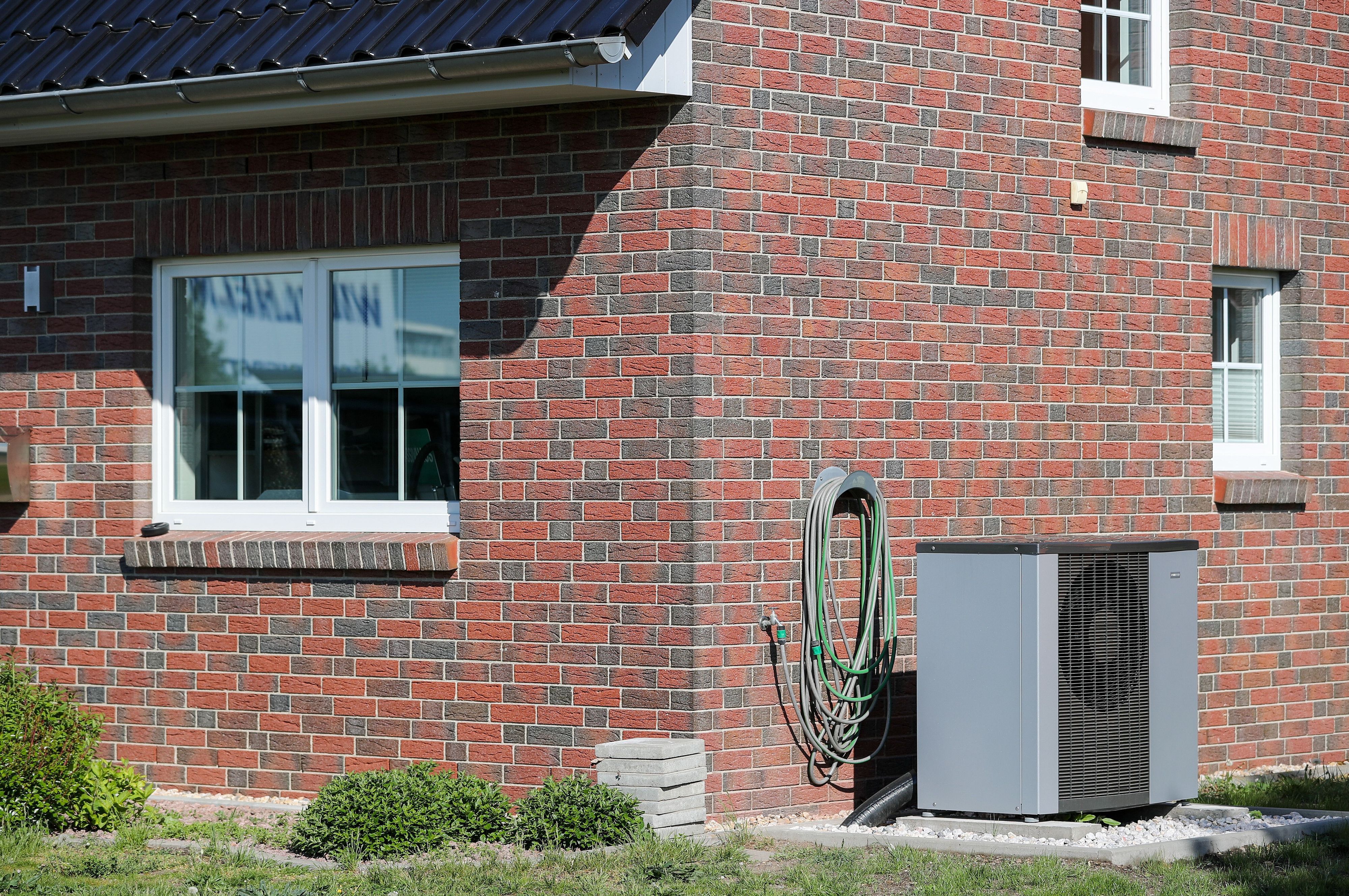Eine Wärmepumpe steht vor einem Haus. Das Gerät kann zwar auch kühlen, trotzdem will die Regierung den Einbau weniger stark fördern. (Symbolbild)