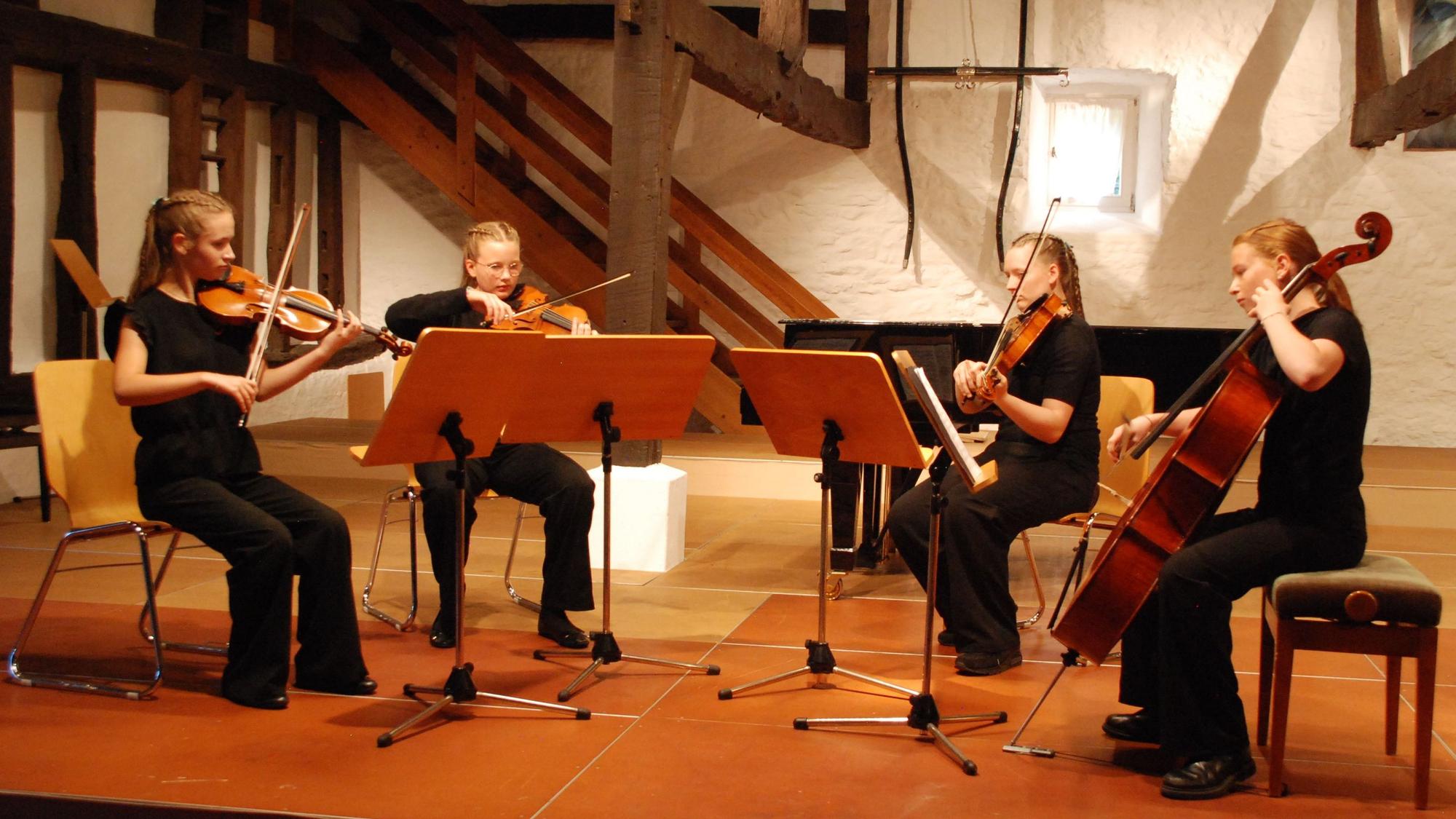 Die vier Musikerinnen sitzen hinter Notenständern und spielen auf ihren Streichinstrumenten.