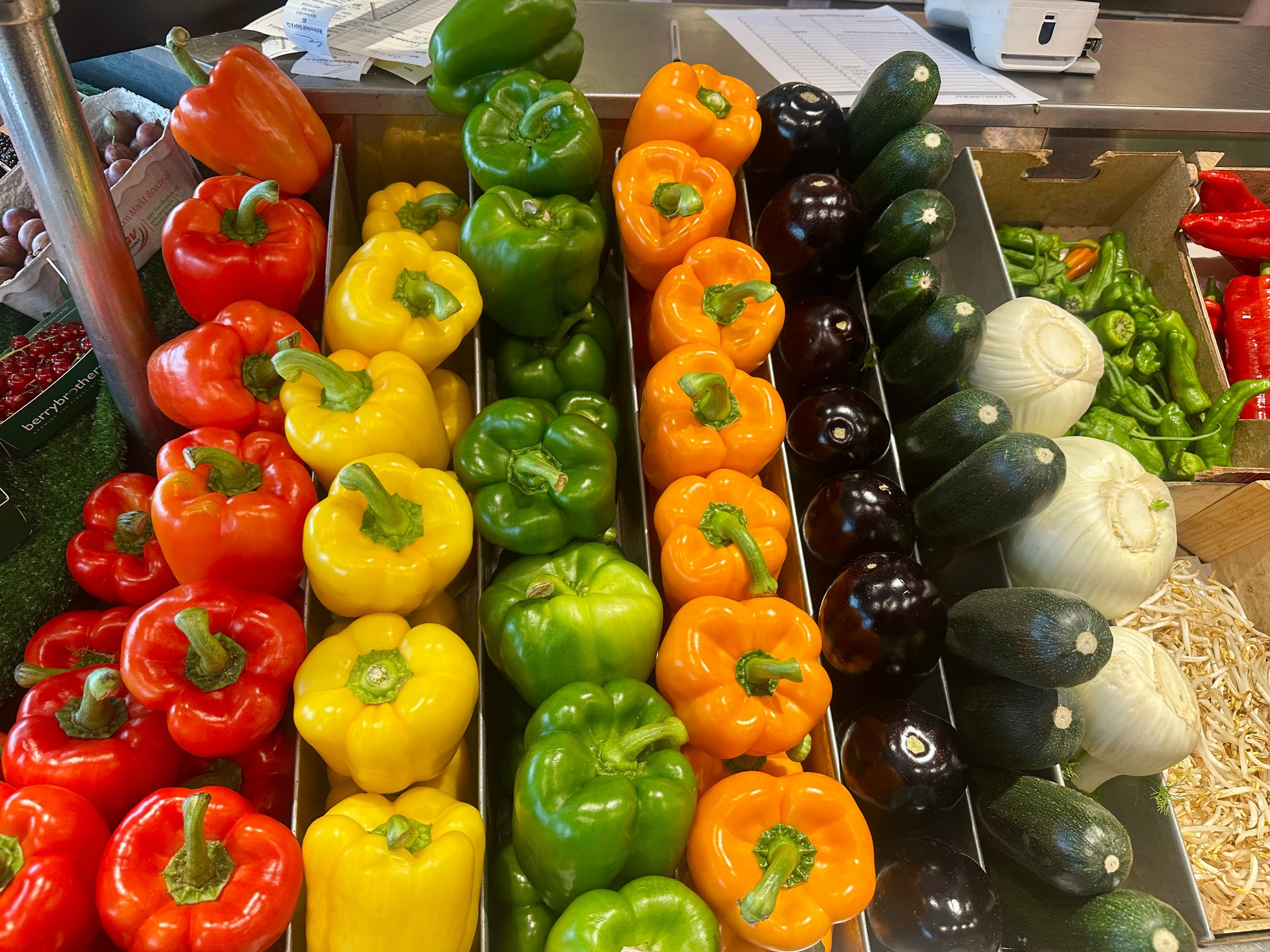 In einer Kiste liegen Paprika in allen Farben, Auberginen und Zucchini ordentlich nebeneinander.