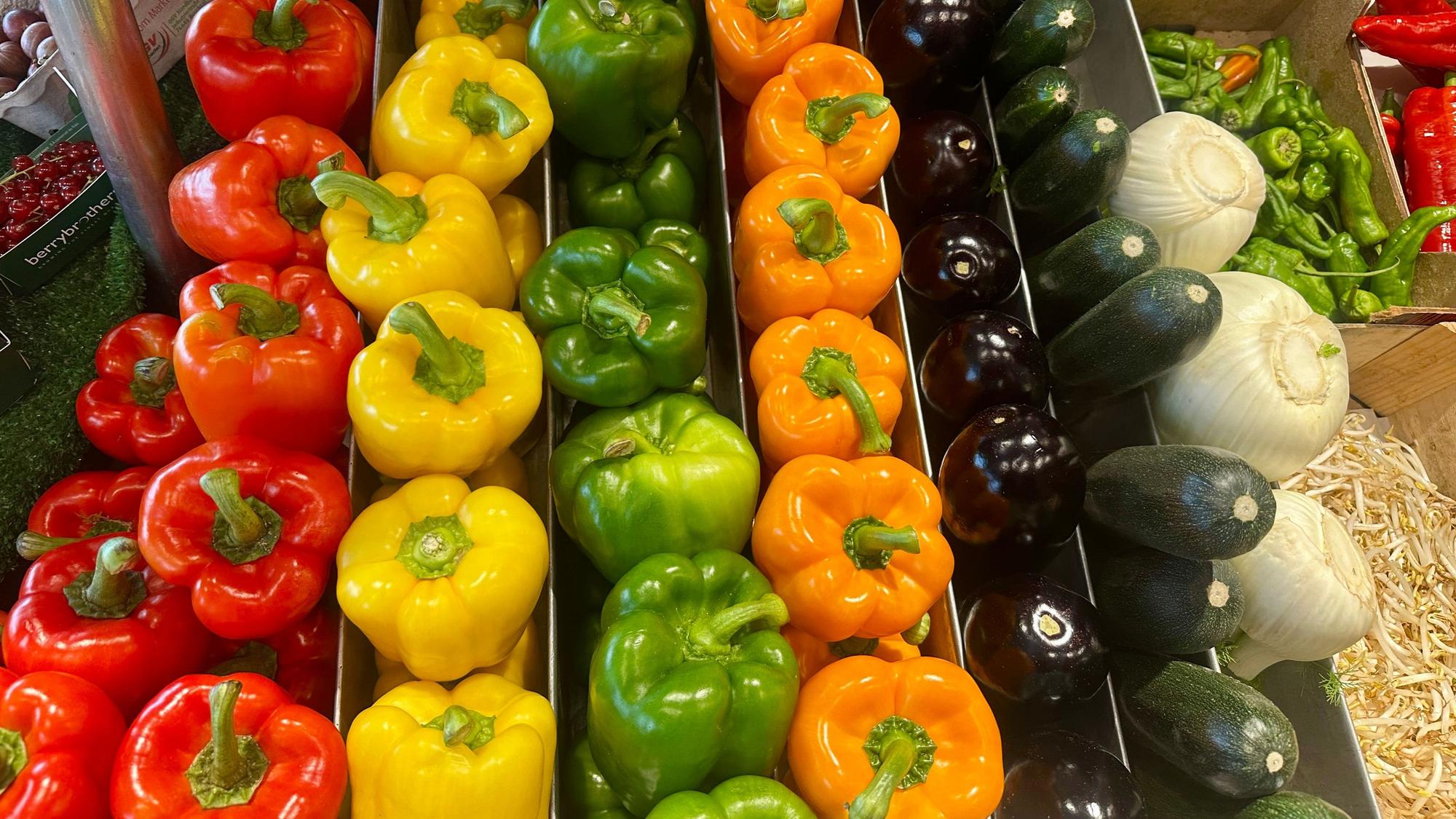 In einer Kiste liegen Paprika in allen Farben, Auberginen und Zucchini ordentlich nebeneinander.