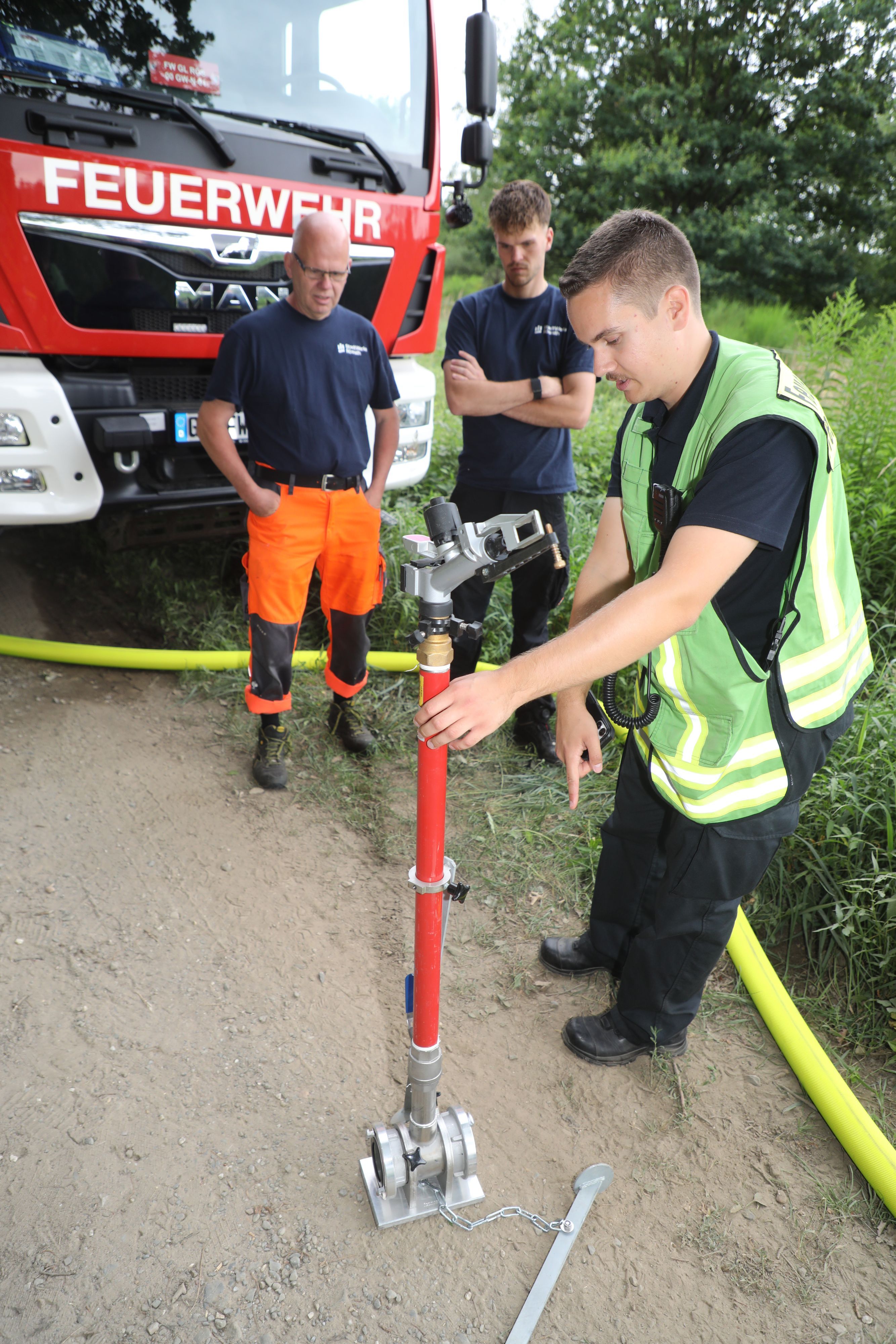 Rösraths Feuerwehrsprecher Luca Meysing zeigt Mitarbeitenden der Stadtwerke Rösrath einen Sprenkler der Kreisregneranlage.