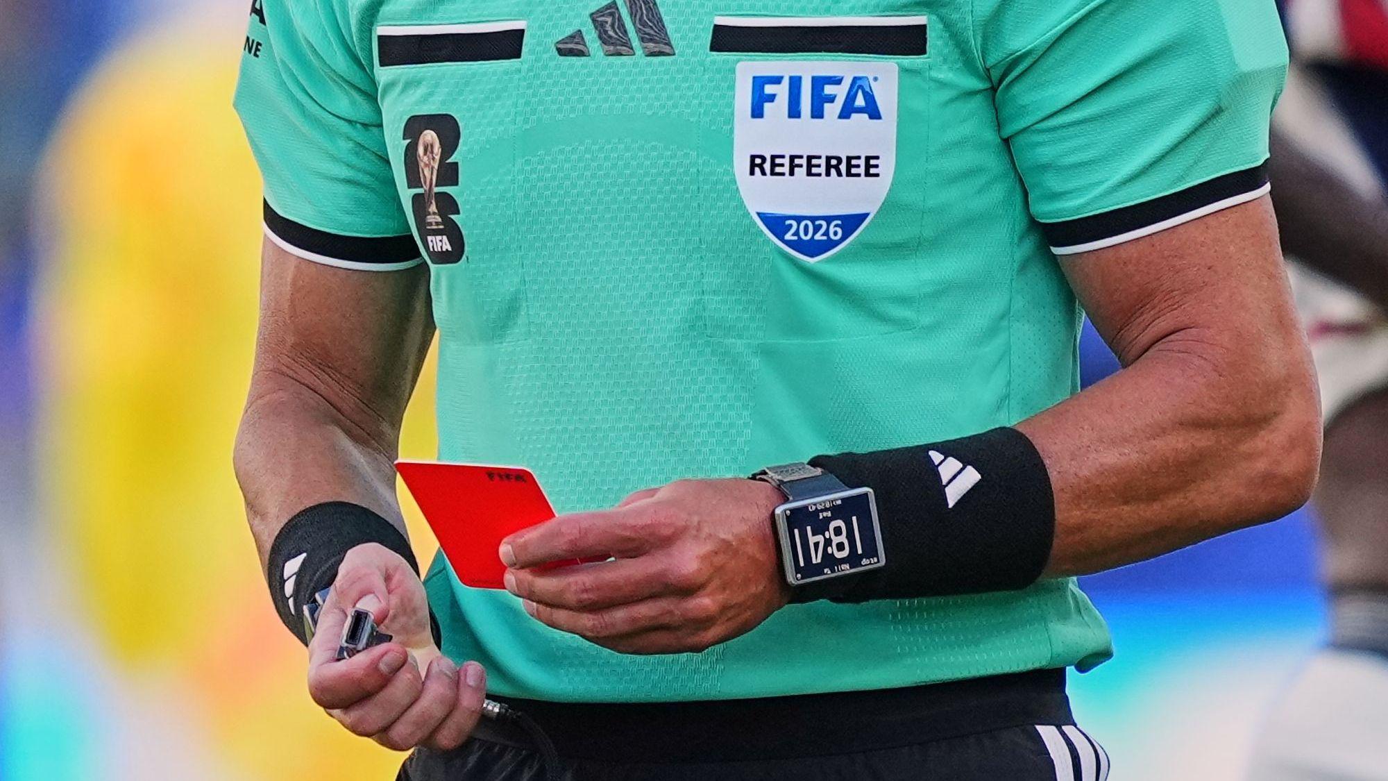 Ein Schiedsrichter der Fifa hält eine Rote Karte in der linken Hand.
