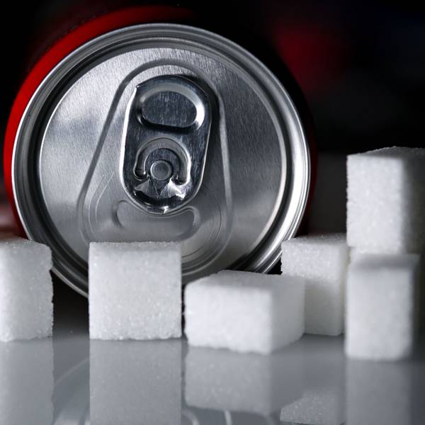 Eine Getränkedose mit einem Softdrink und zahlreiche Zuckerwürfel liegen auf einem Tisch. Die Bundesregierung plant eine Zuckersteuer. (Symbolbild)