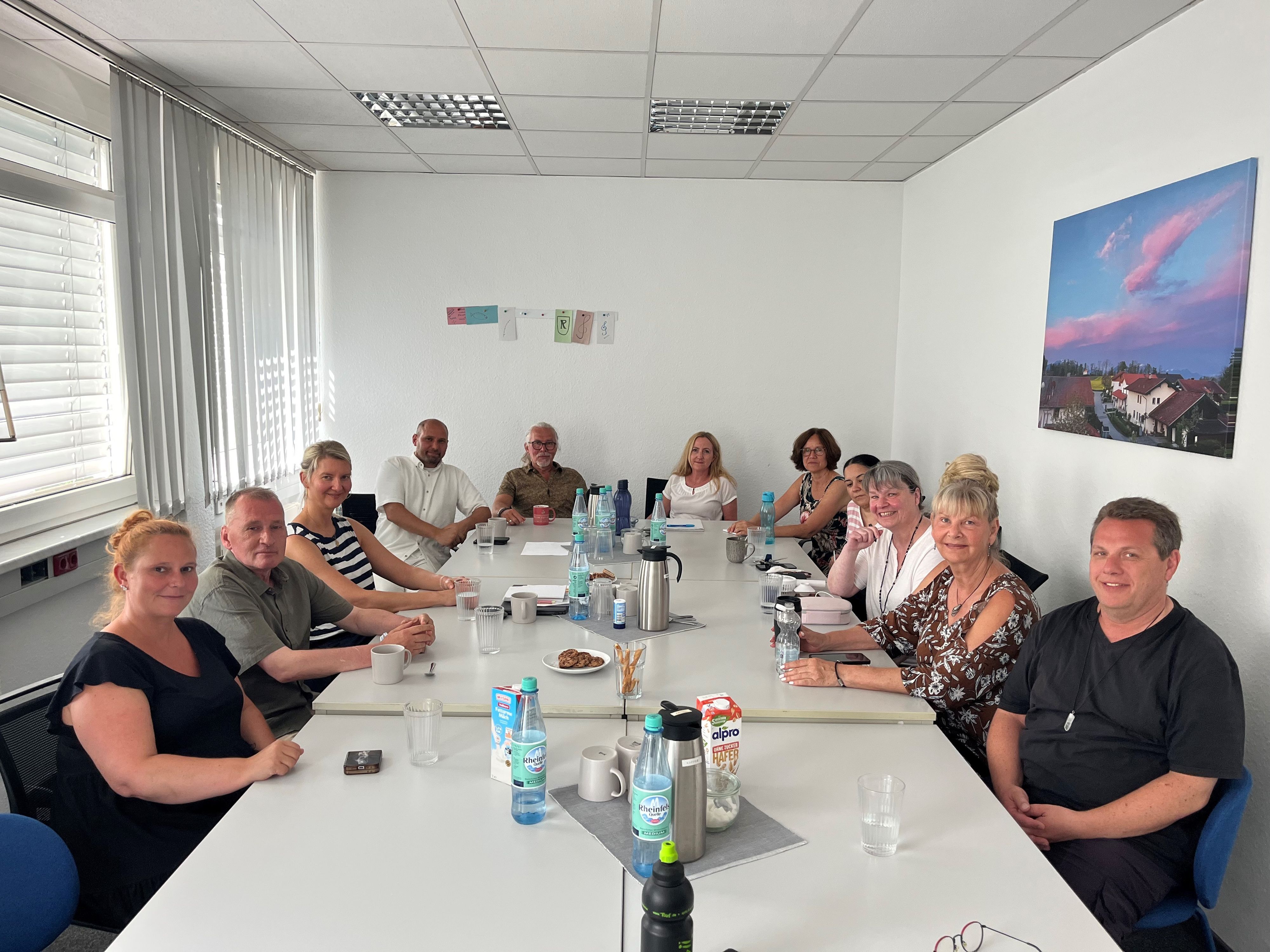Elf Personen sitzen an einem Tisch.
