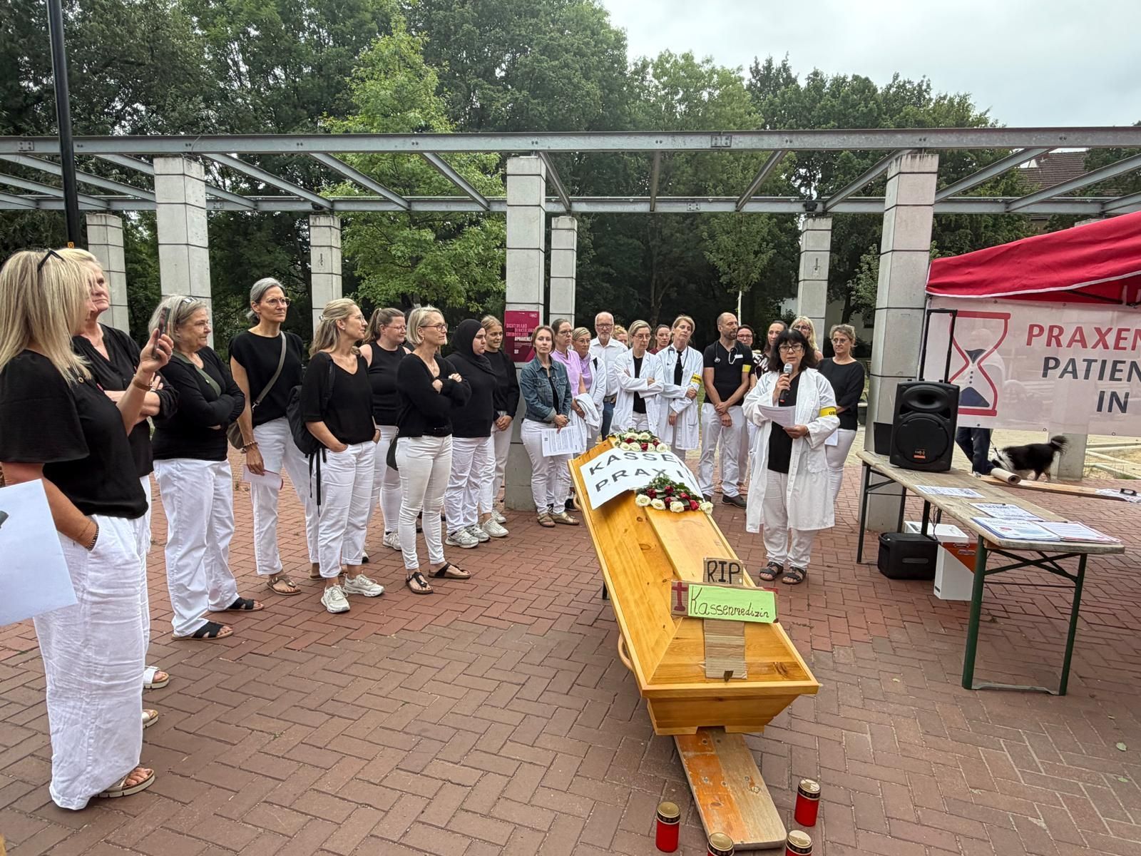 Mediziner stehen an einem Sarg beim Protest in Leichlingen