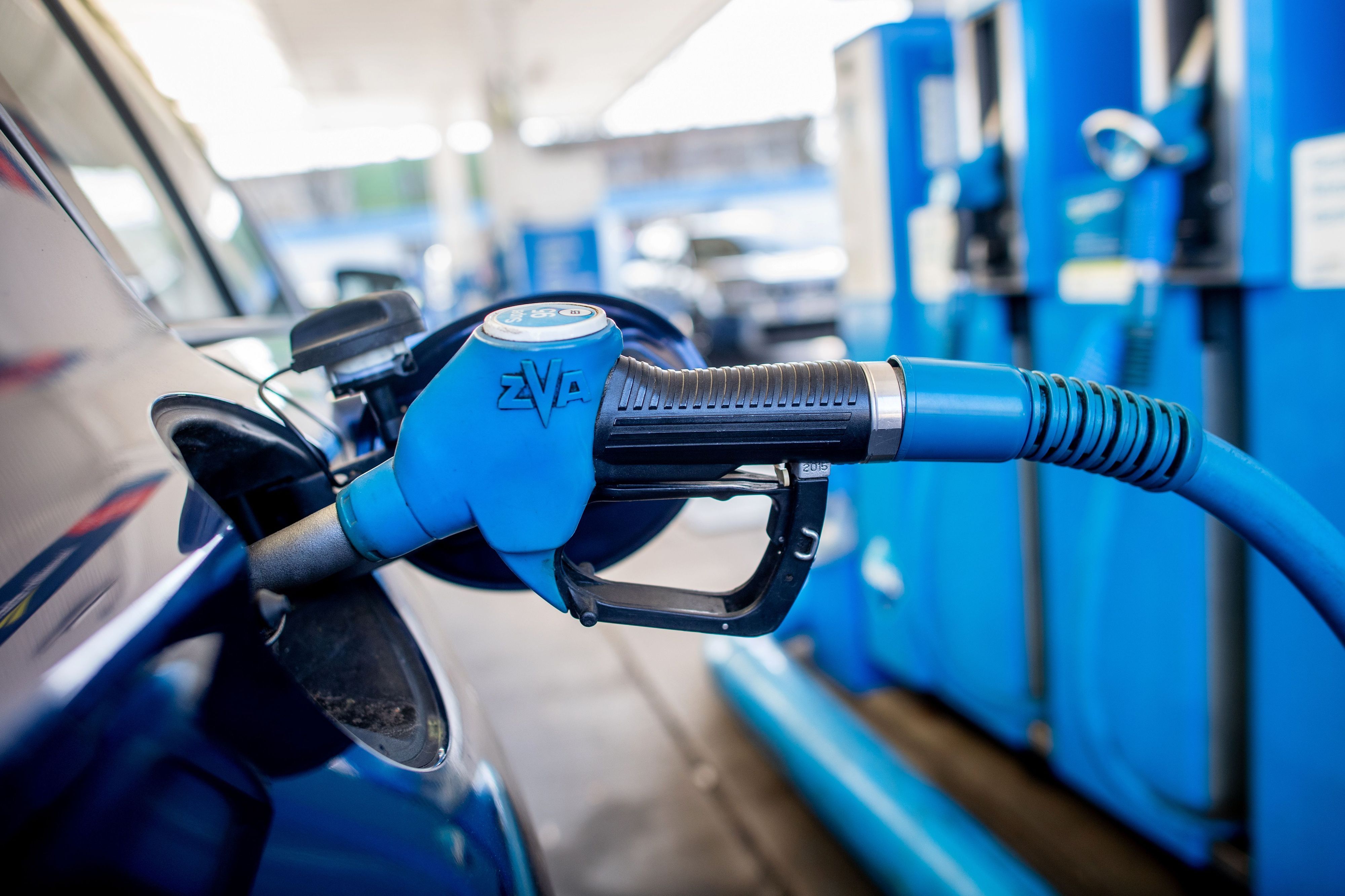 Eine Zapfpistole mit der Aufschrift „Super 95“ steckt an einer Tankstelle in der Tanköffnung eines Fahrzeugs.