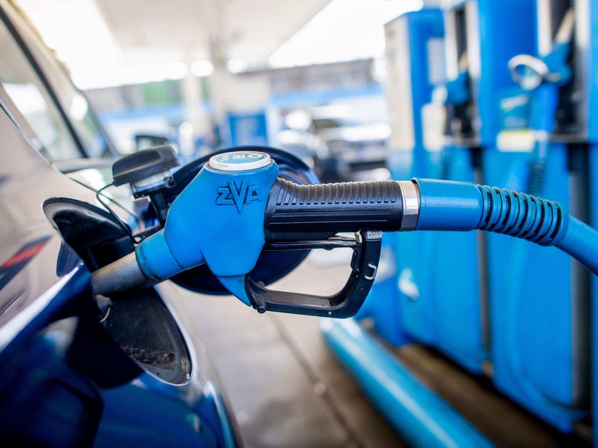 Eine Zapfpistole mit der Aufschrift „Super 95“ steckt an einer Tankstelle in der Tanköffnung eines Fahrzeugs.