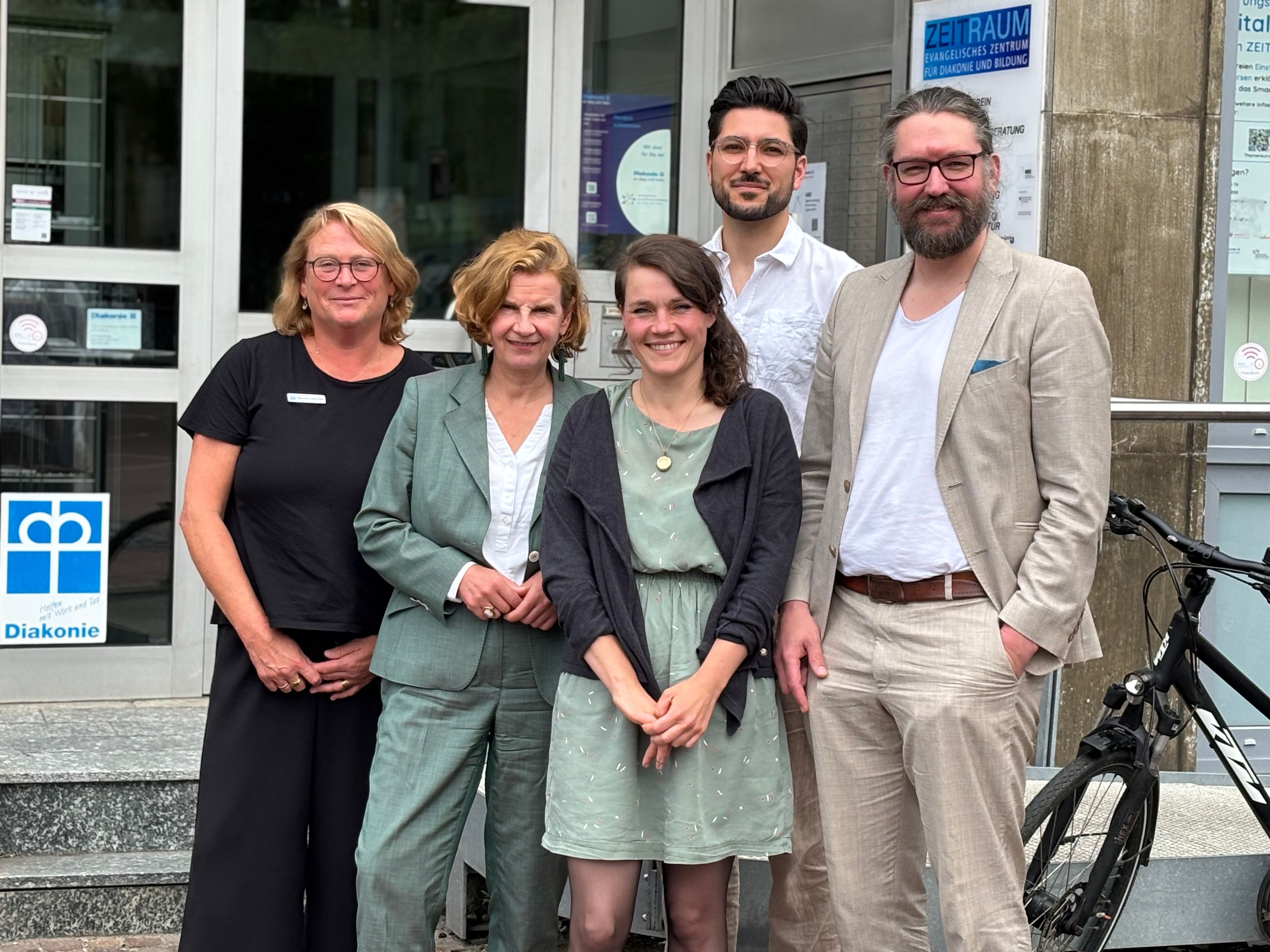 Die Obengenannten, drei Frauen und zwei Männer, stehen vor den Räumlichkeiten der Diakonie in Siegburg und posieren für die Aufnahme.