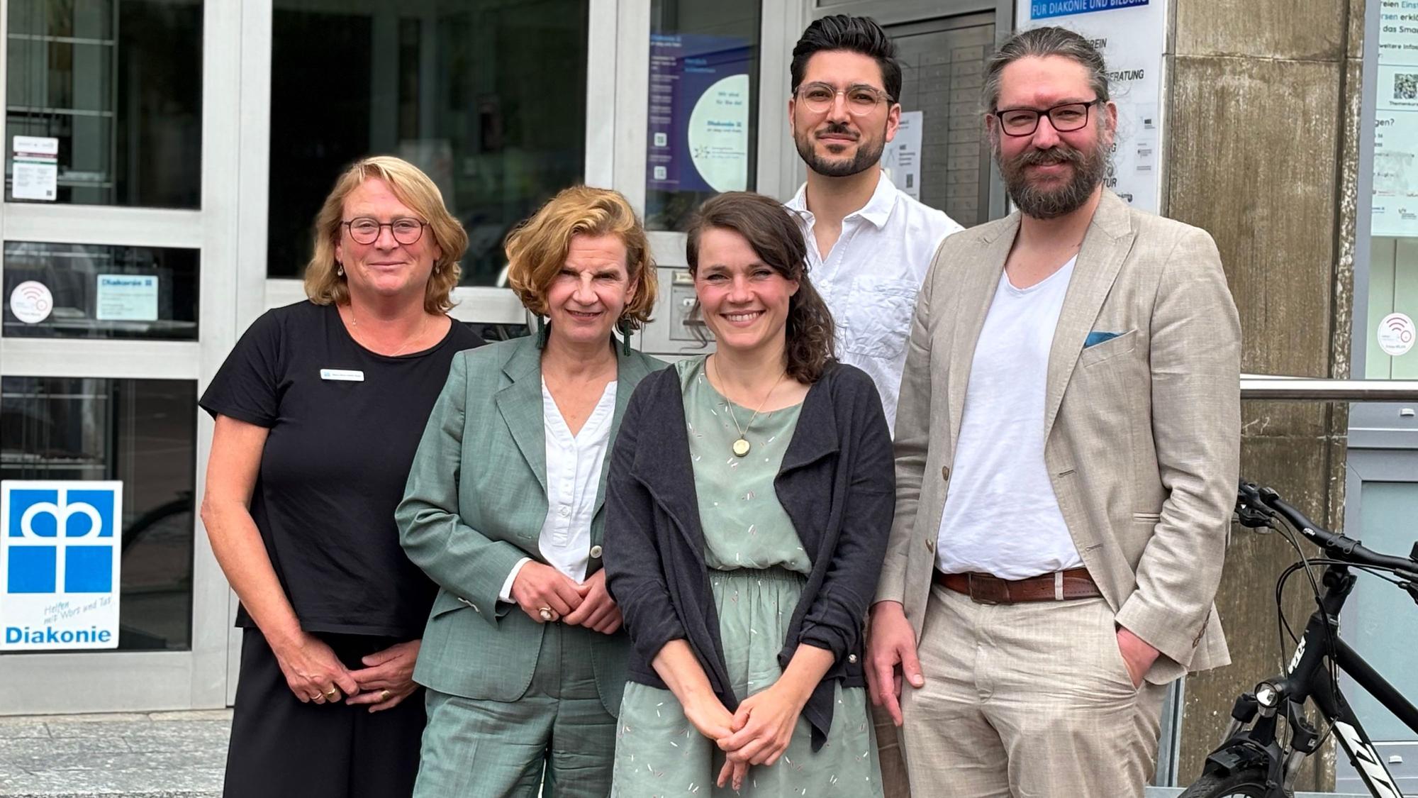 Die Obengenannten, drei Frauen und zwei Männer, stehen vor den Räumlichkeiten der Diakonie in Siegburg und posieren für die Aufnahme.