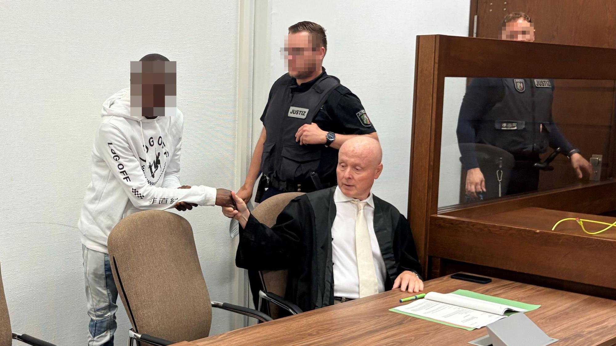 Der Angeklagte begrüßt seinen Verteidiger Mario Geuenich beim Prozess im Kölner Landgericht.